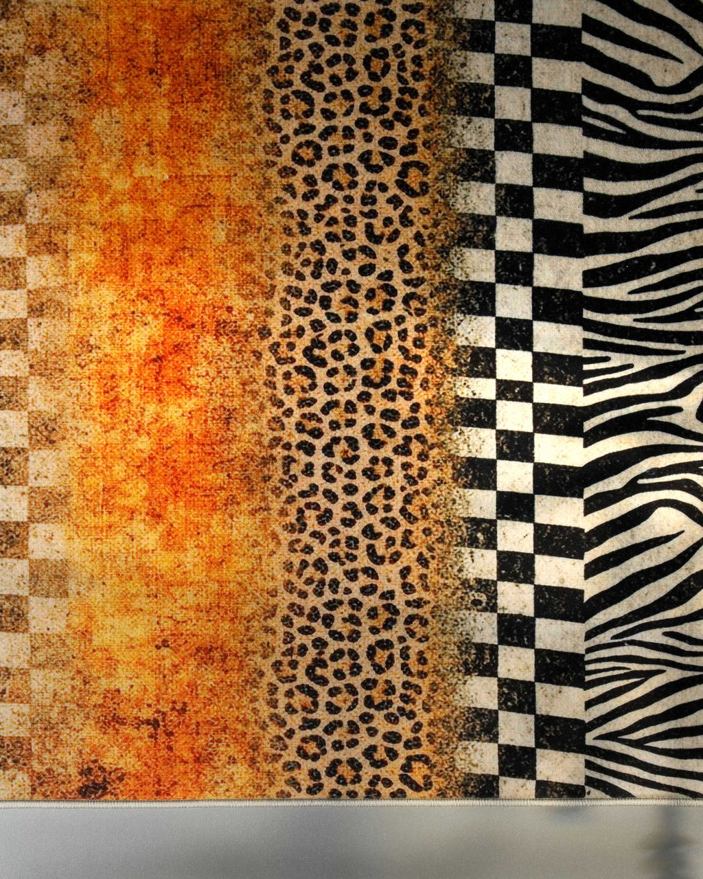 Detailansicht des Badteppichs Jungle Stripes mit vertikal verlaufenden Zebra-, Leoparden- und Schachbrettmustern.