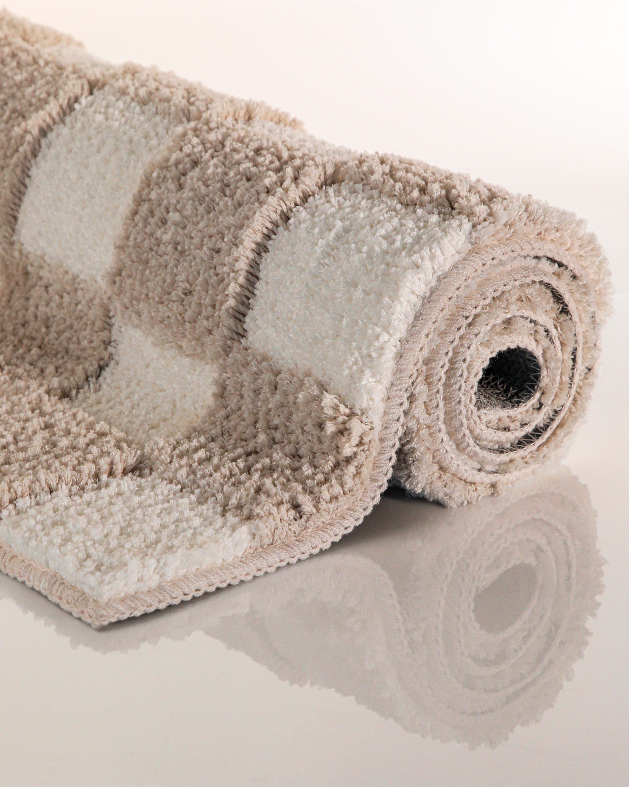 Badteppich von BathKing by WECONhome Bobbi Beige aufgerollt auf hellem Hintergrund, Seitenansicht zeigt Florhöhe und Musterverlauf