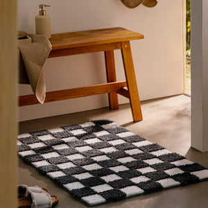 {"class" => "product-thumbnails__image", "alt" => "Badteppich von BathKing by WECONhome Bobbi Anthrazit Grau im Badezimmer neben Holzbank auf hellem Boden liegend, rechteckige Matte mit Karomuster"}
