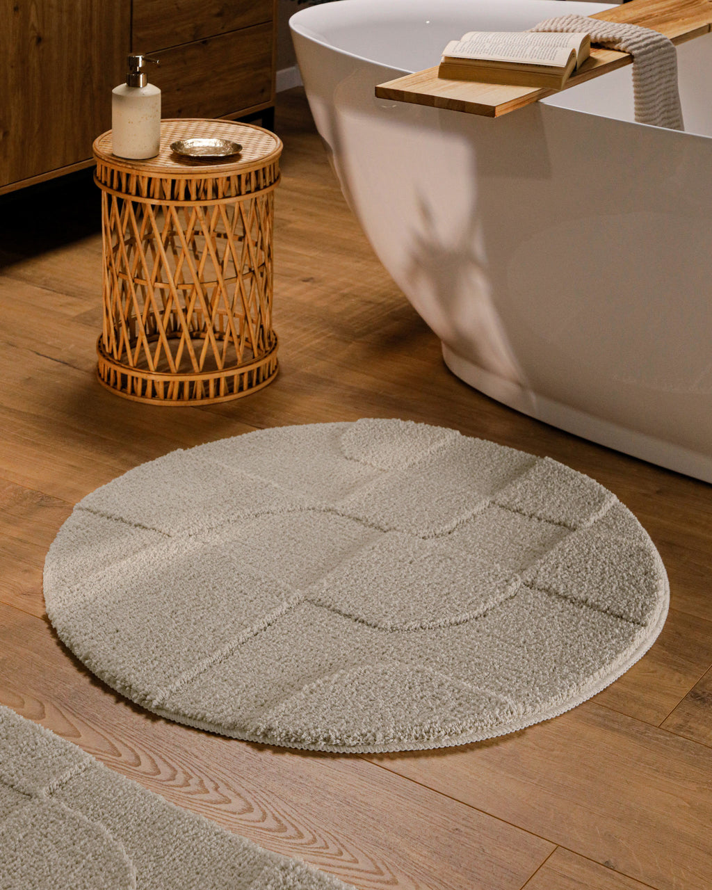 Runder Badteppich von BathKing by WECONhome Davie Grau im Badezimmer vor Badewanne auf Holzboden, strukturiertes Linienrelief im Flor sichtbar