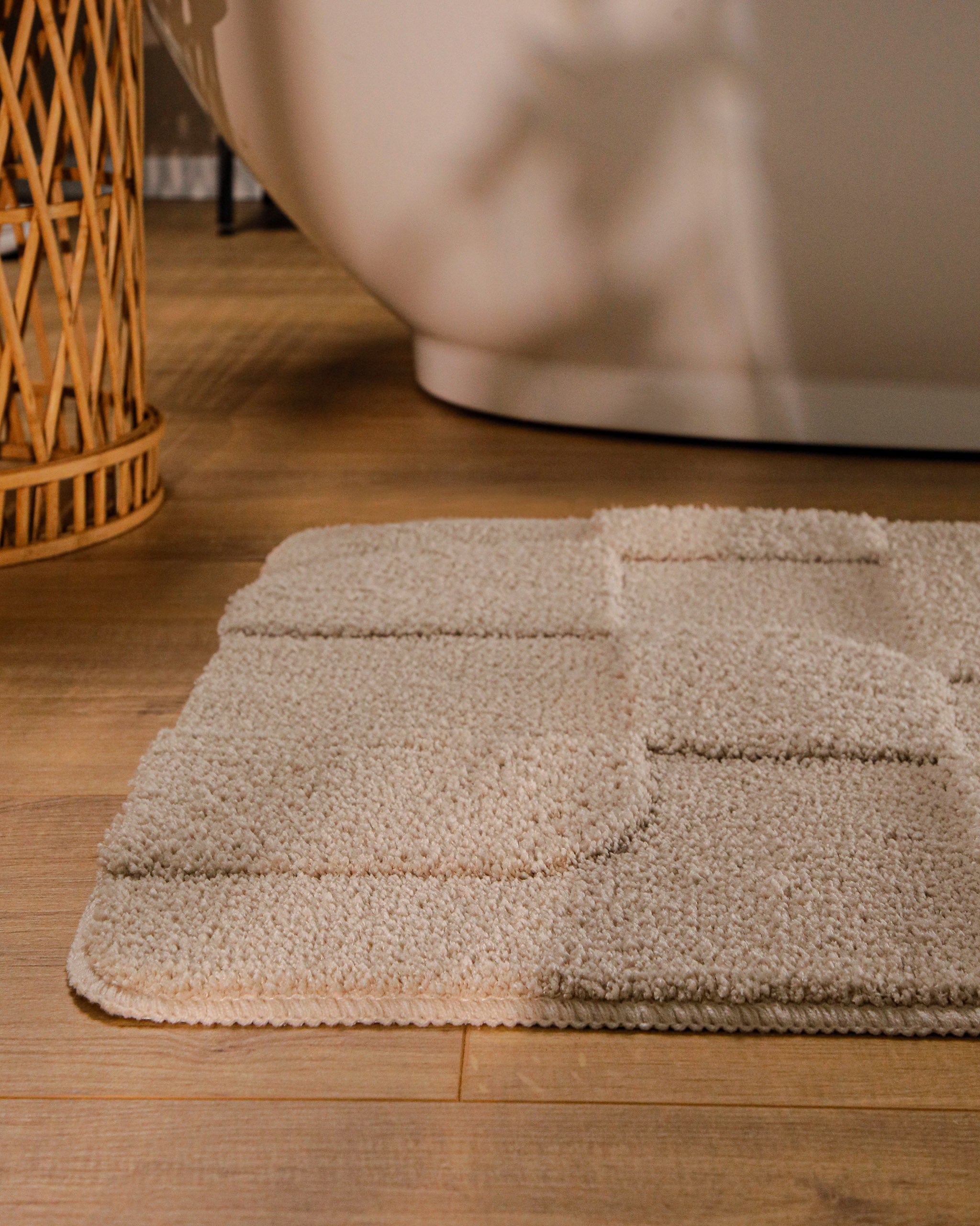 Badteppich von BathKing by WECONhome Davie Sand Beige runde Matte im Badezimmer vor Badewanne, Strukturmuster im Flor auf Holzboden sichtbar