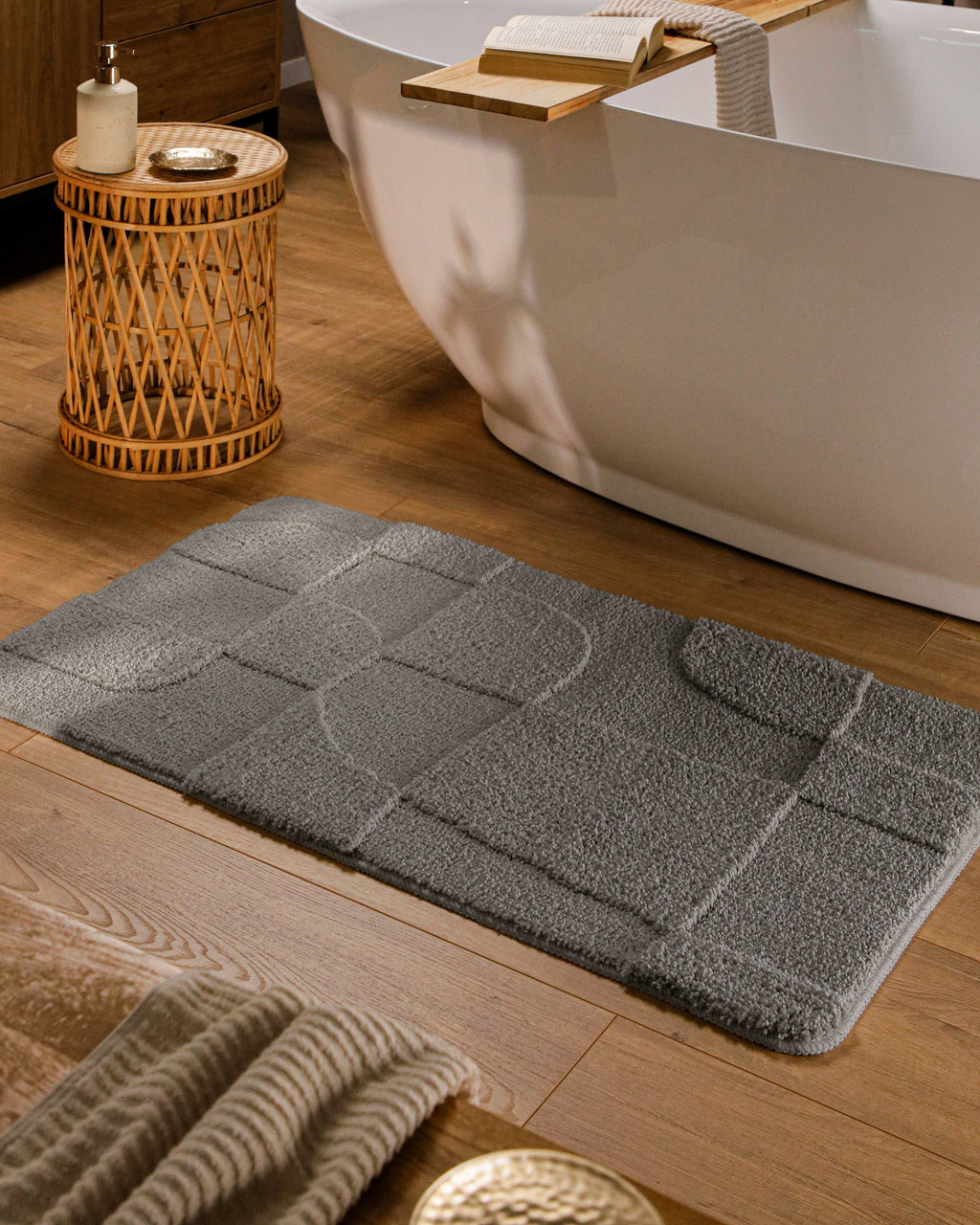 Badteppich von BathKing by WECONhome Davie Basalt Grau rechteckig im Badezimmer vor Badewanne auf Holzboden liegend, Strukturmuster im Flor sichtbar