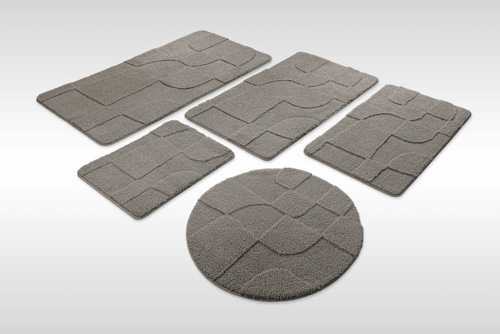 Badteppich von BathKing by WECONhome Davie Basalt Grau Set aus rechteckigen und runden Badmatten, mehrere Größen auf hellem Hintergrund angeordnet