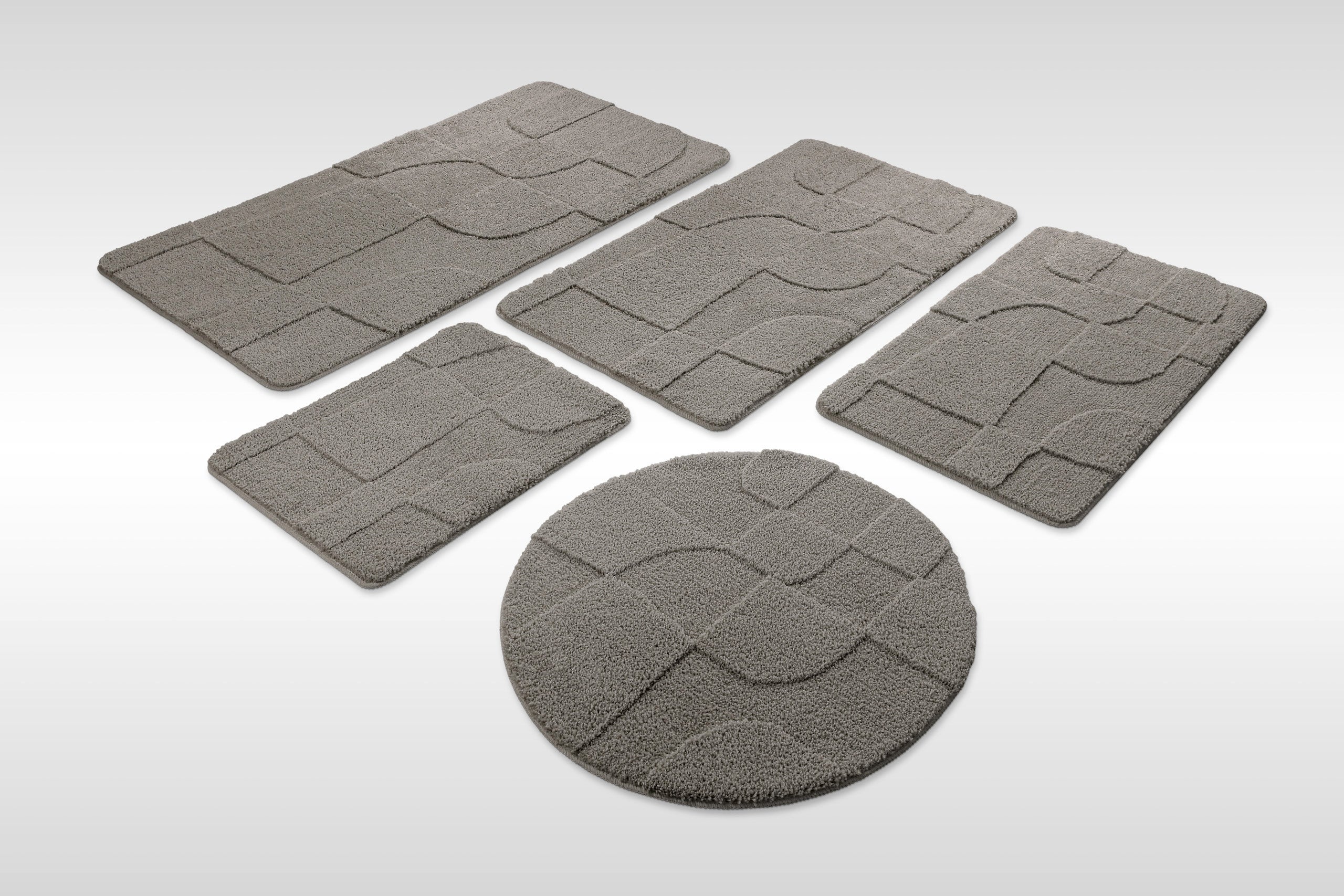 Badteppich von BathKing by WECONhome Davie Basalt Grau Set aus rechteckigen und runden Badmatten, mehrere Größen auf hellem Hintergrund angeordnet