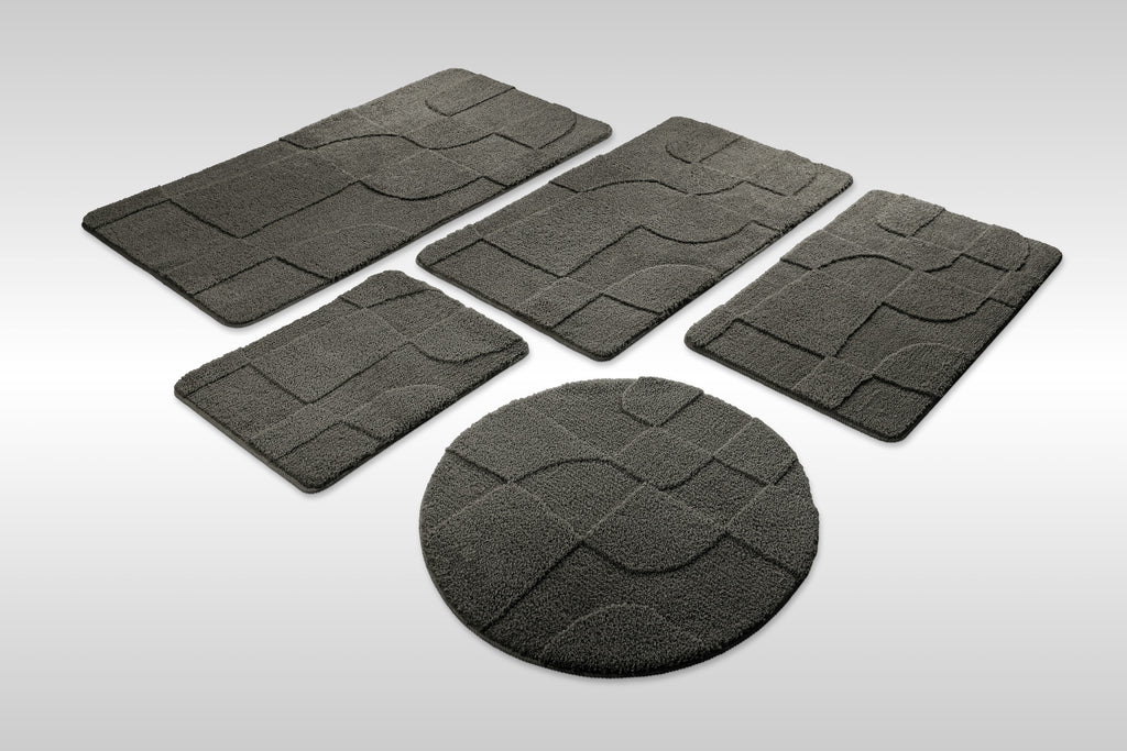Badteppich von BathKing by WECONhome Davie Anthrazit Grau Set aus rechteckigen und runden Badmatten, mehrere Größen auf hellem Hintergrund angeordnet