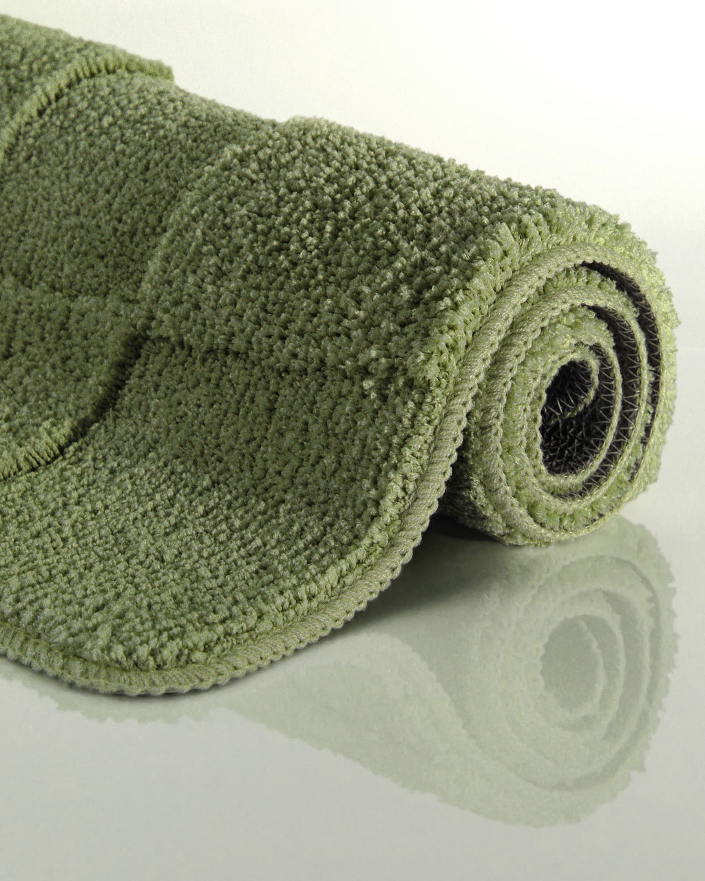 Badteppich von BathKing by WECONhome Davie Reseda Grün aufgerollt auf hellem Hintergrund, Seitenansicht zeigt Florhöhe und Teppichkante