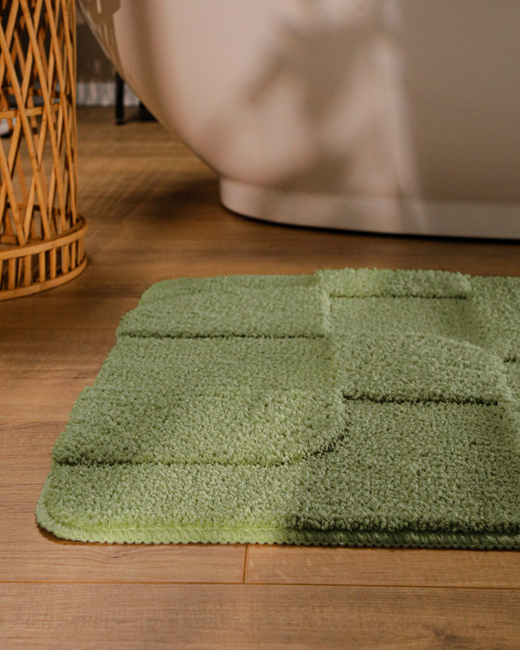 Badteppich von BathKing by WECONhome Davie Reseda Grün runde Matte im Badezimmer vor Badewanne, Strukturmuster im Flor auf Holzboden sichtbar
