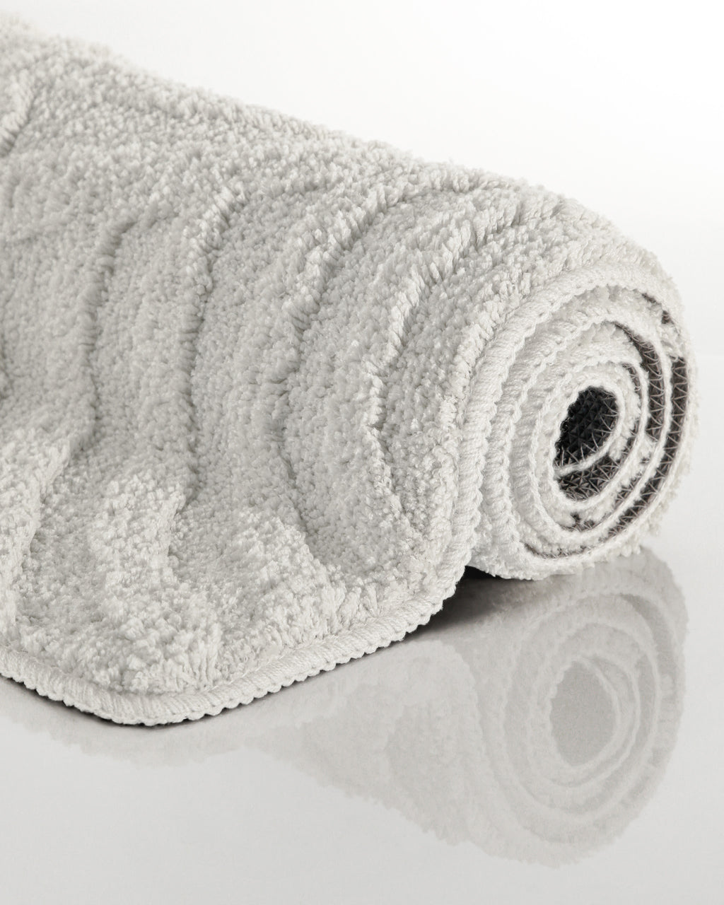 Badteppich von BathKing by WECONhome Fiete Weiß aufgerollt auf hellem Hintergrund, Seitenansicht zeigt Florhöhe und Teppichkante