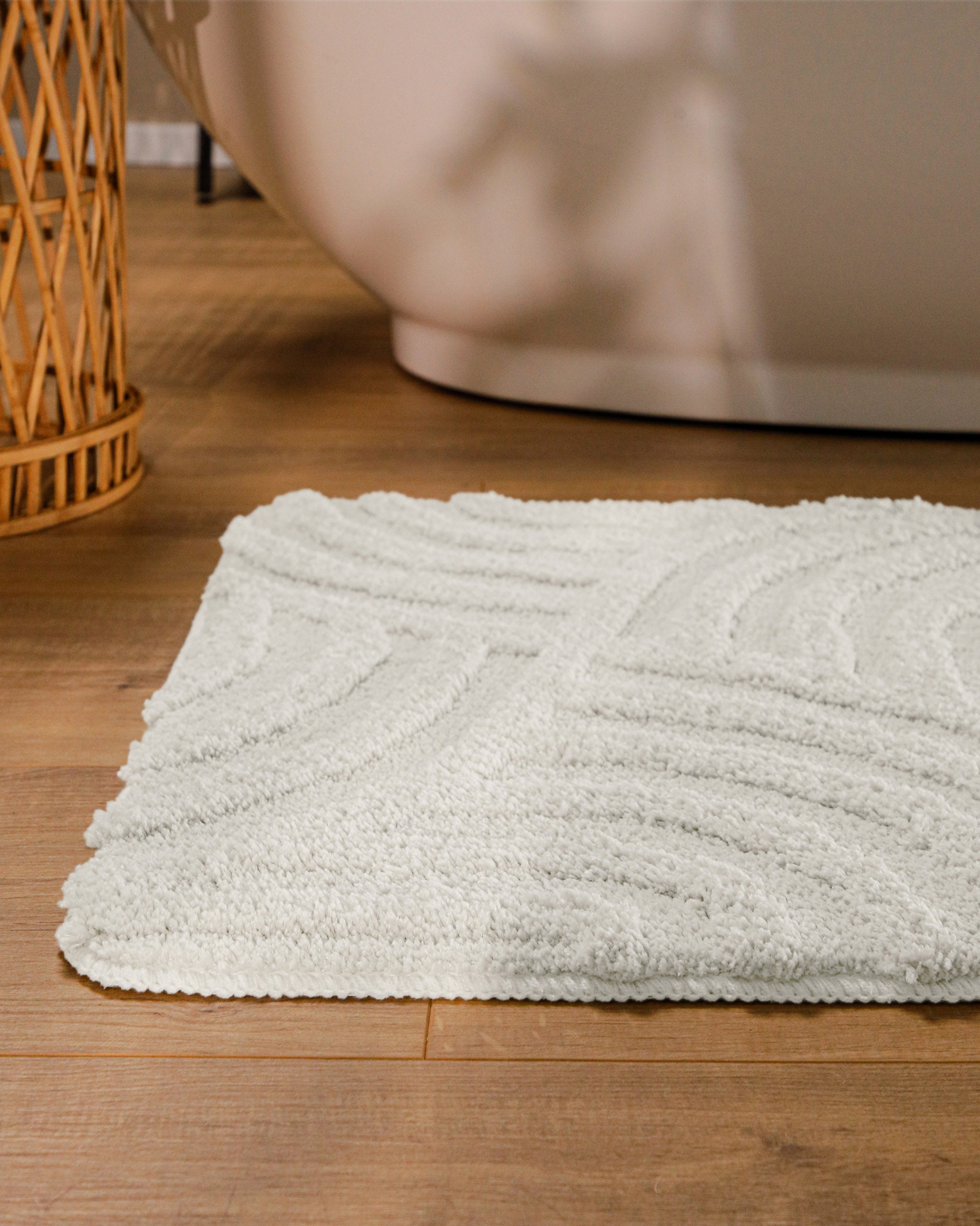 Badteppich von BathKing by WECONhome Fiete Weiß runde Matte im Badezimmer vor Badewanne, Strukturmuster im Flor auf Holzboden sichtbar