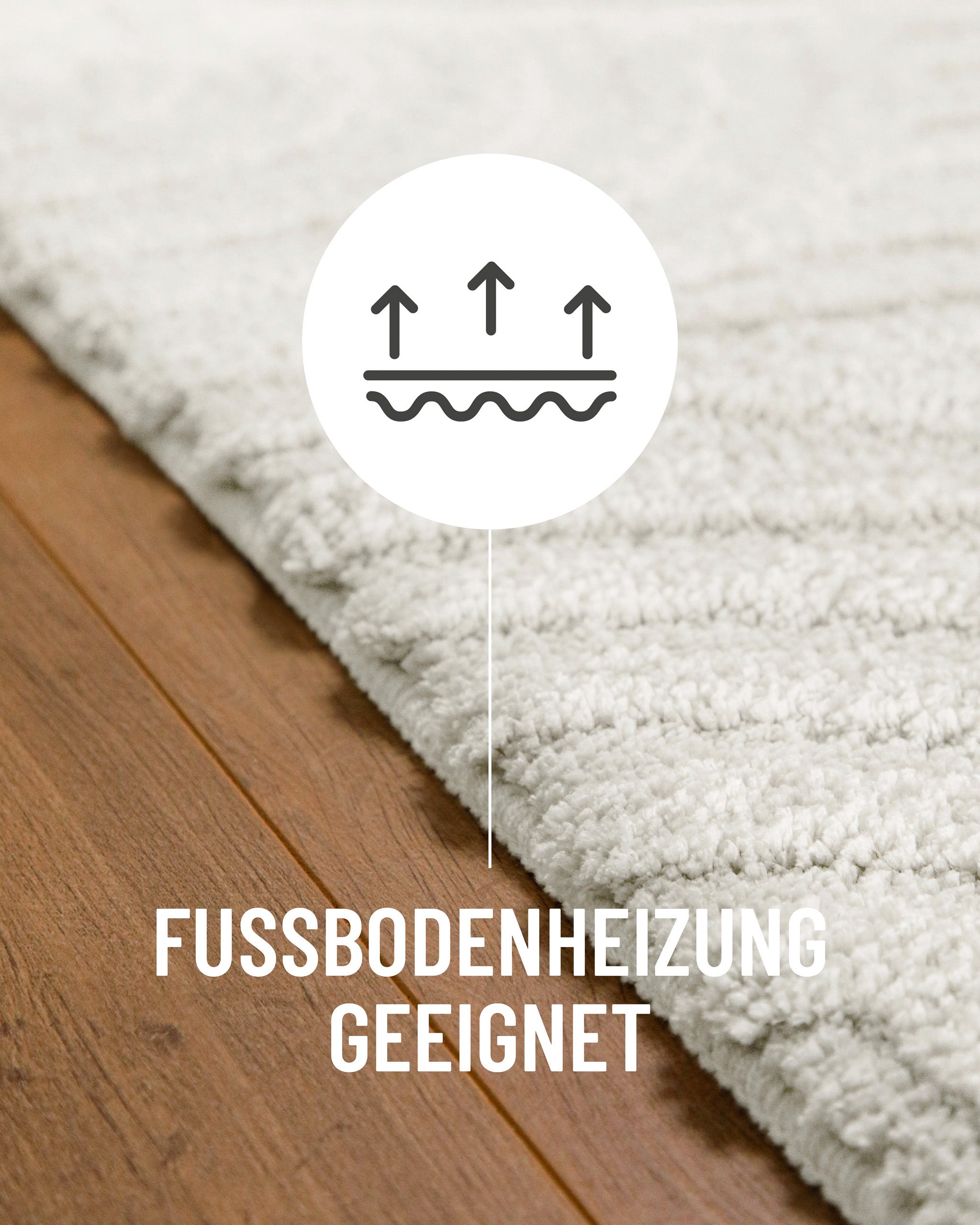 Badteppich von BathKing by WECONhome Fiete Weiß Detail auf Holzfußboden mit Symbol für Fußbodenheizung, Nahaufnahme von Flor und Teppichkante