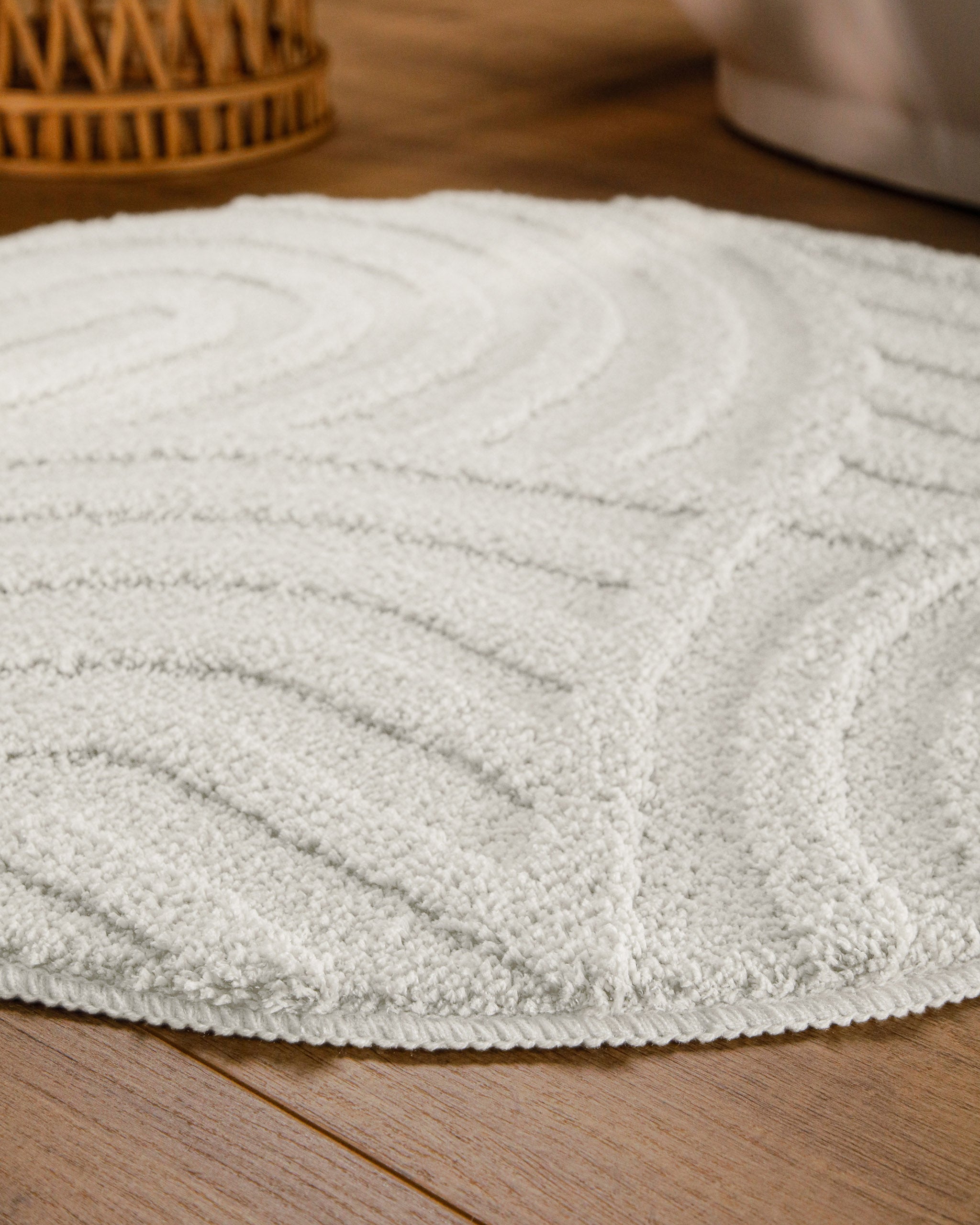 Badteppich von BathKing by WECONhome Fiete Weiß rund im Badezimmer auf Holzboden neben Badewanne, Florstruktur und Linienrelief erkennbar