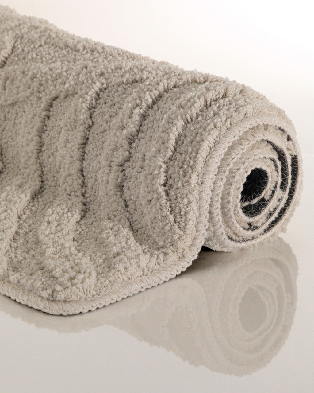 Badteppich von BathKing by WECONhome Fiete Grau aufgerollt auf hellem Hintergrund, Seitenansicht zeigt Florhöhe und Teppichkante