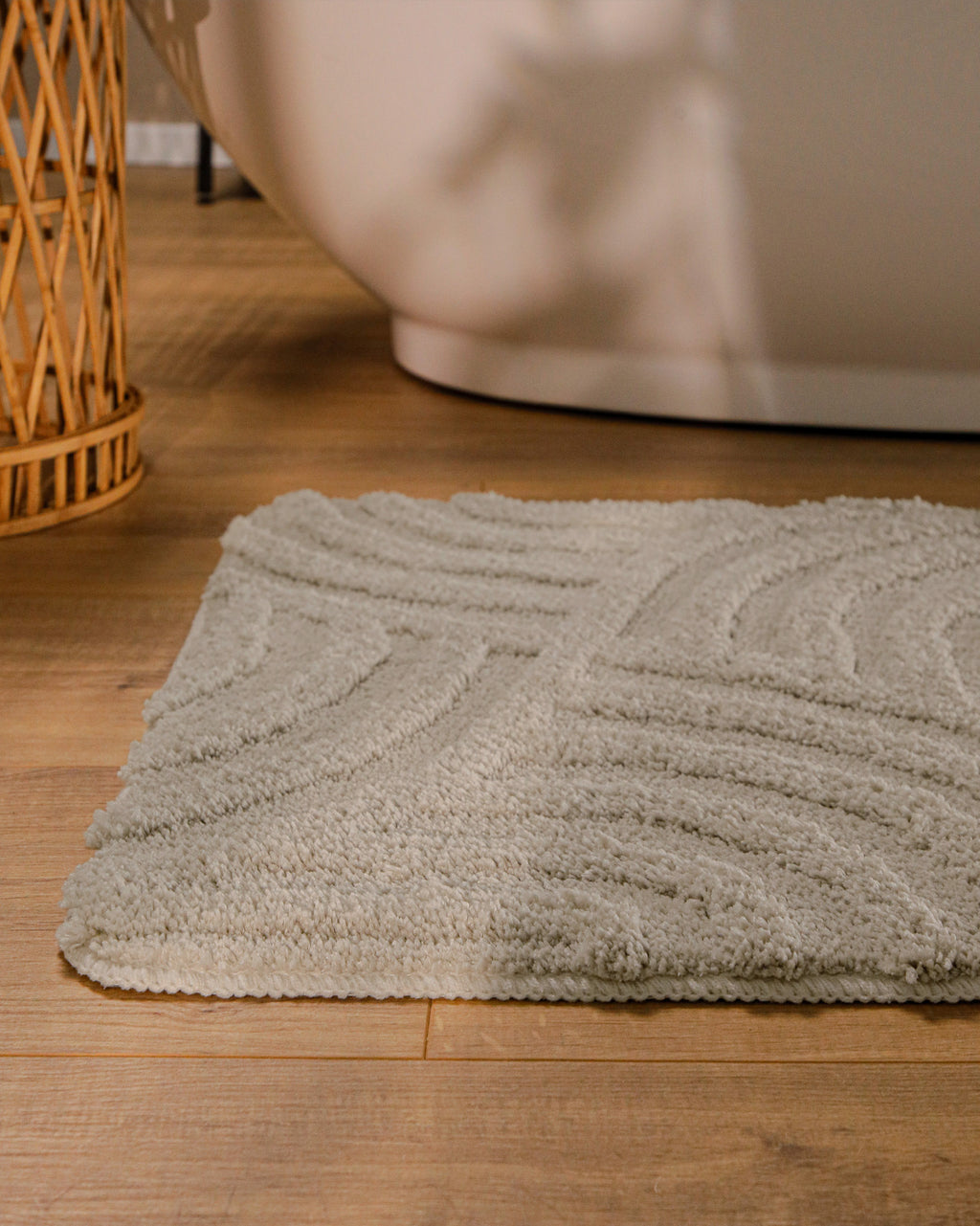 Badteppich von BathKing by WECONhome Fiete Grau runde Matte im Badezimmer vor Badewanne, Strukturmuster im Flor auf Holzboden sichtbar