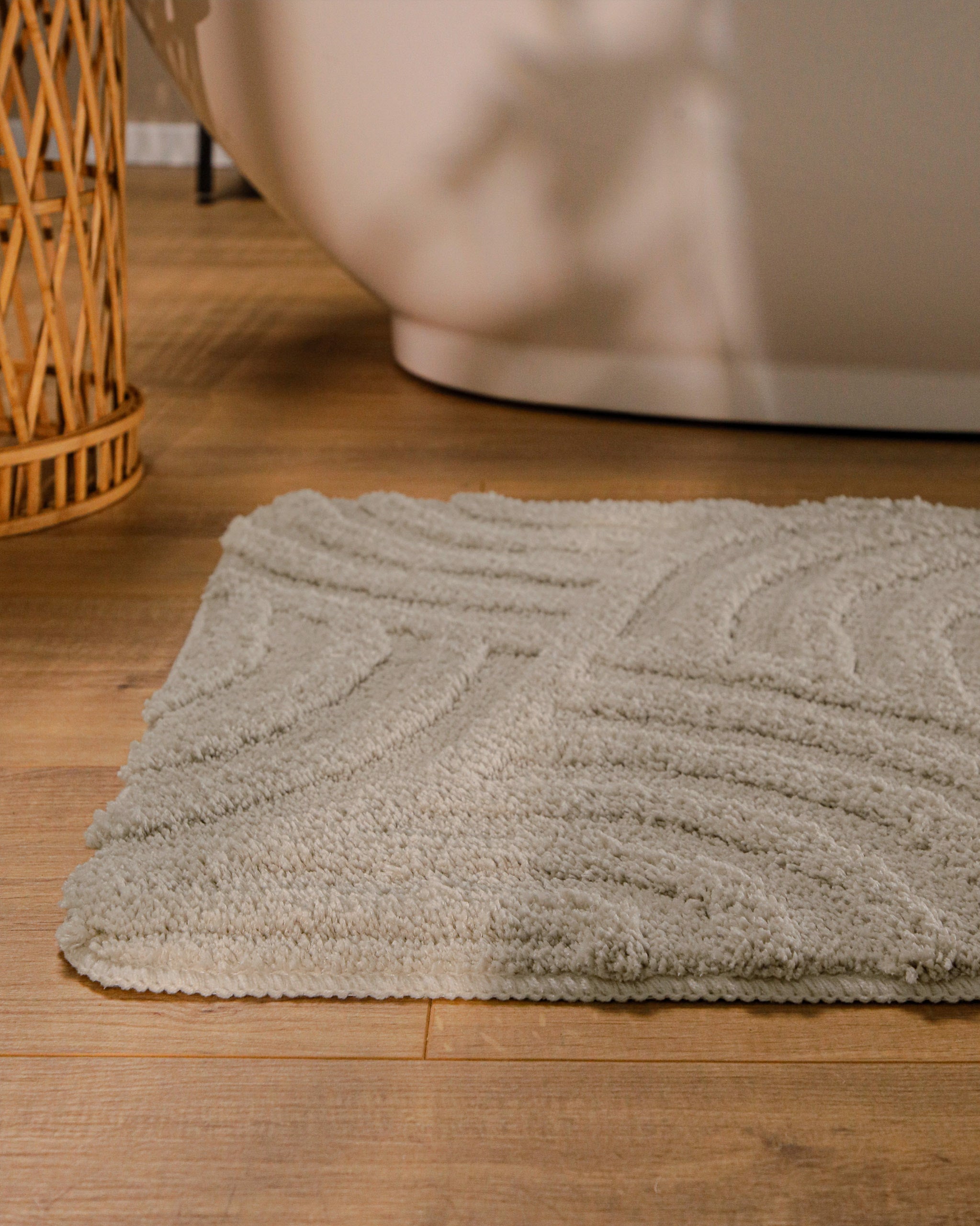 Badteppich von BathKing by WECONhome Fiete Grau runde Matte im Badezimmer vor Badewanne, Strukturmuster im Flor auf Holzboden sichtbar