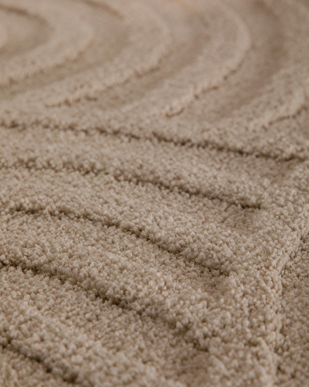 Badteppich von BathKing by WECONhome Fiete Sand Beige rund Detail der Teppichkante mit Hinweisen zu maschinengetufteter Verarbeitung