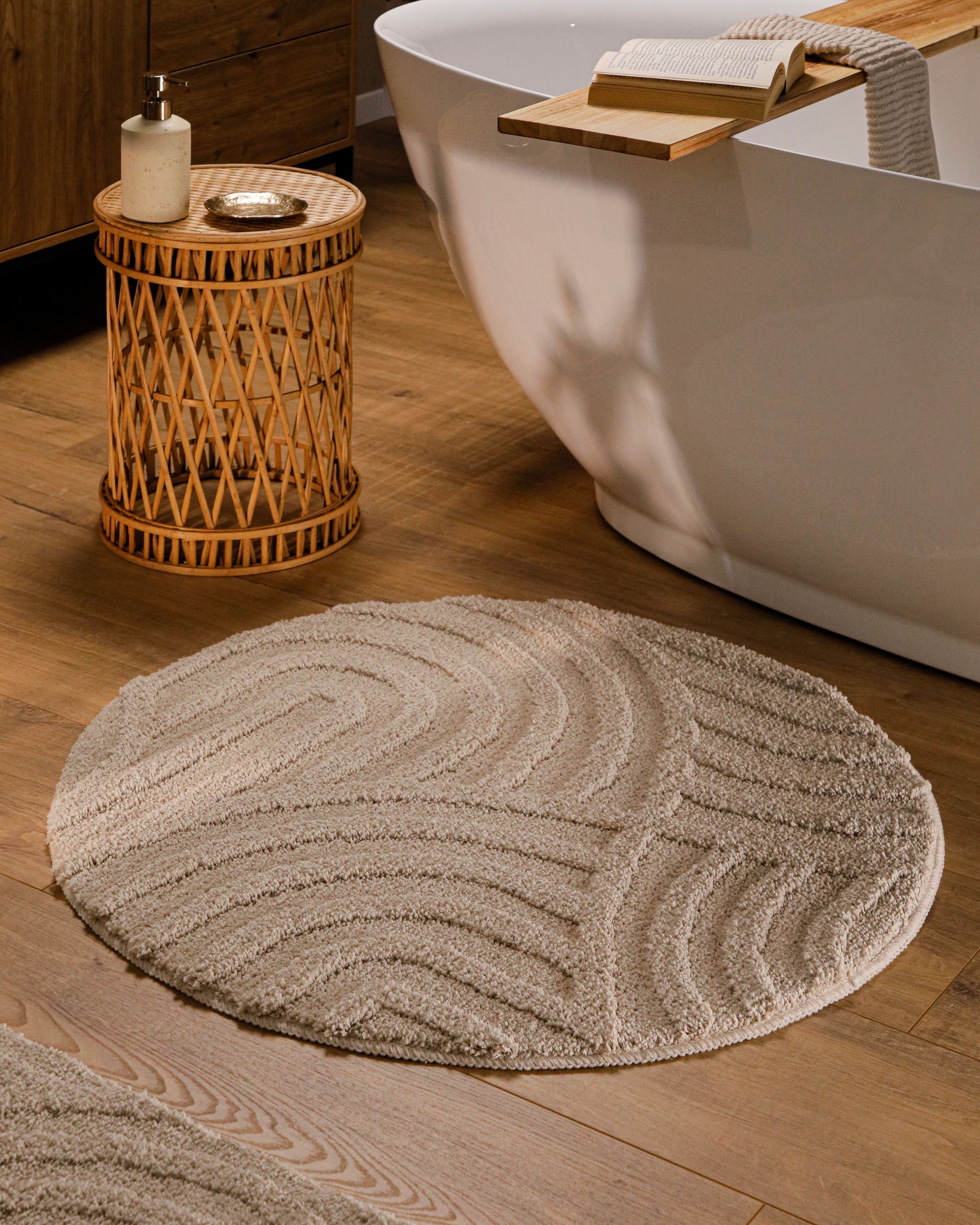 Badteppich von BathKing by WECONhome Fiete Sand Beige Detailaufnahme mit umgeschlagener Ecke, Hinweisgrafik zur rutschhemmenden Rückseite und Waschbarkeit