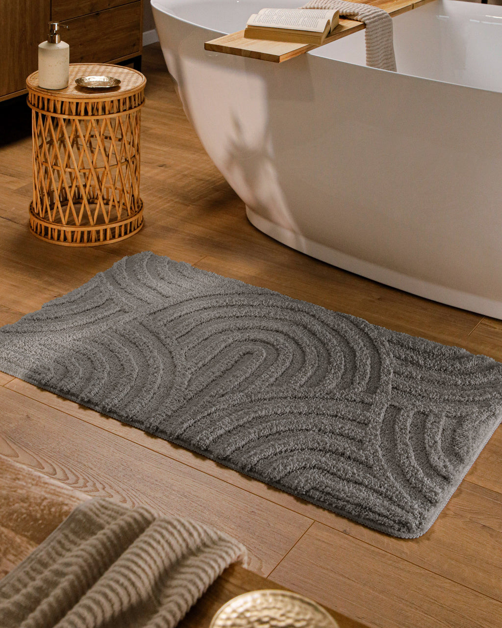 Badteppich von BathKing by WECONhome Fiete Basalt Grau rechteckig im Badezimmer vor Badewanne auf Holzboden liegend, Strukturmuster im Flor sichtbar