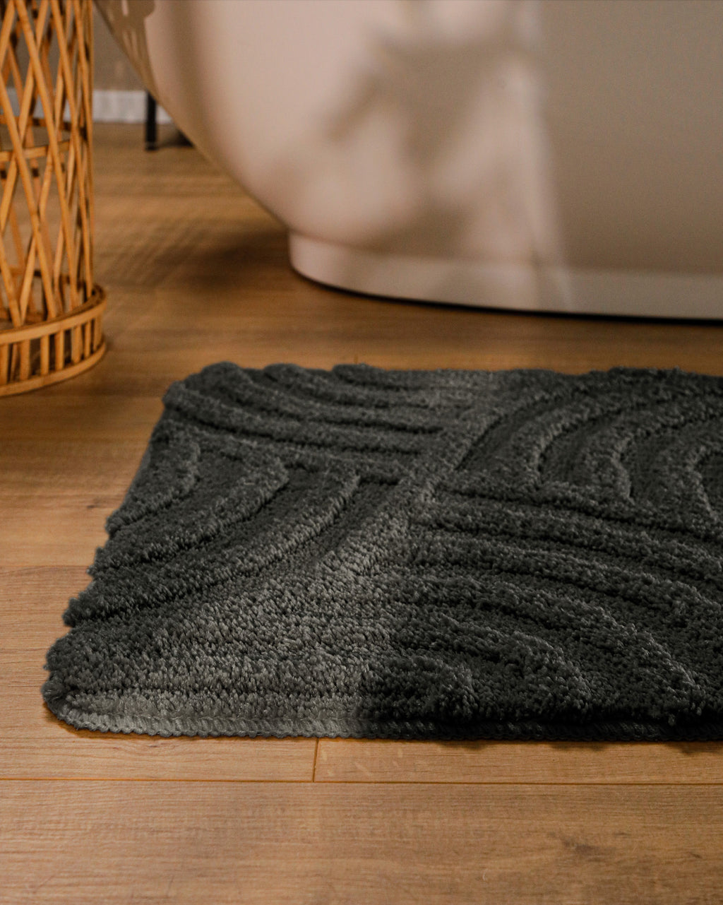 Badteppich von BathKing by WECONhome Fiete Anthrazit Grau runde Matte im Badezimmer vor Badewanne, Strukturmuster im Flor auf Holzboden sichtbar