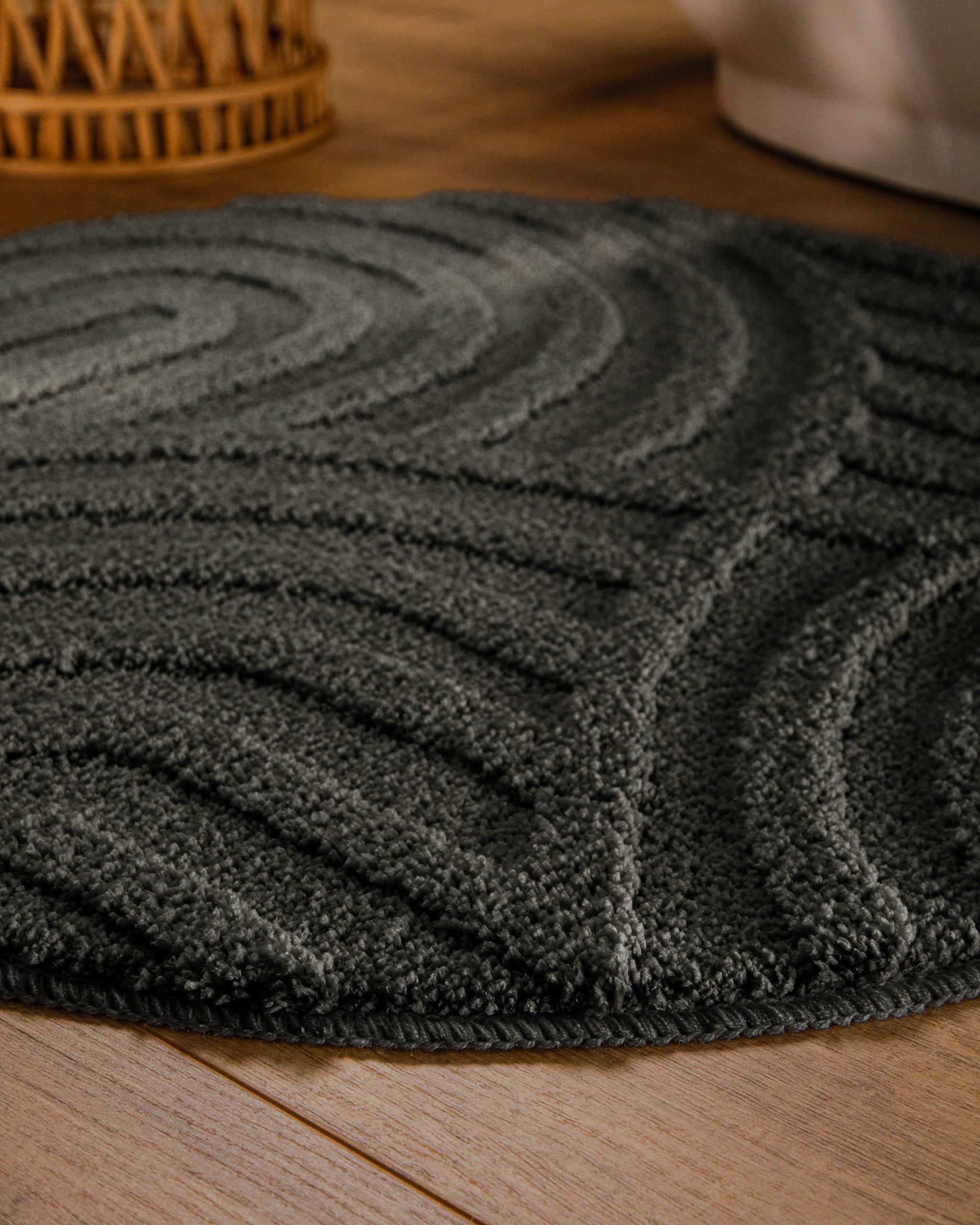 Badteppich von BathKing by WECONhome Fiete Anthrazit Grau rund im Badezimmer auf Holzboden neben Badewanne, Florstruktur und Linienrelief erkennbar