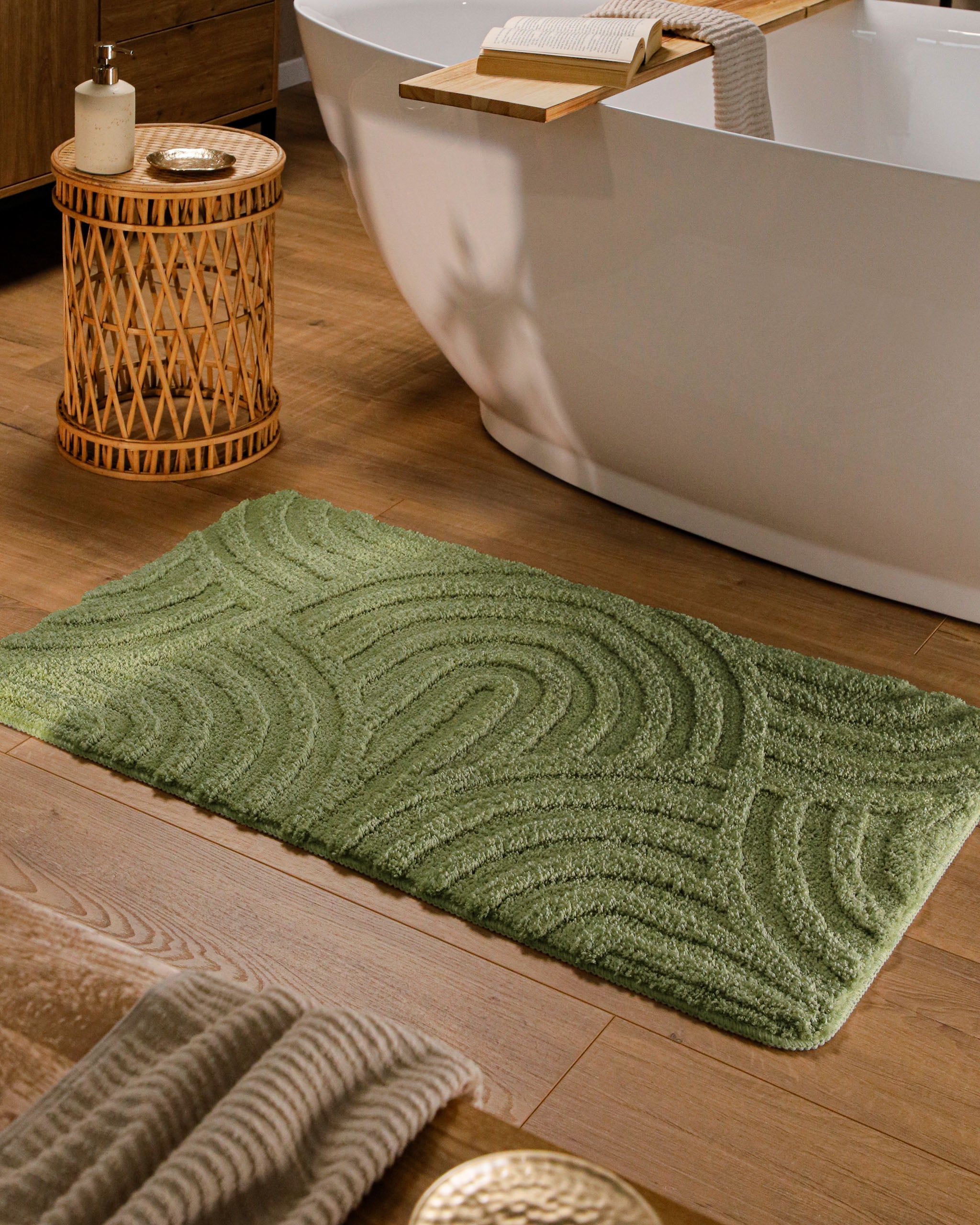 Badteppich von BathKing by WECONhome Fiete Reseda Grün rechteckig im Badezimmer vor Badewanne auf Holzboden liegend, Strukturmuster im Flor sichtbar