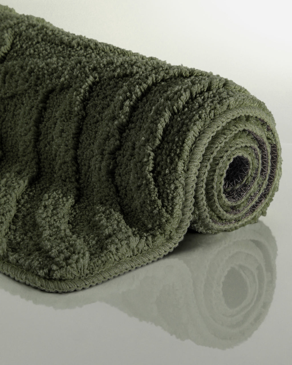 Badteppich von BathKing by WECONhome Fiete Kiefer Grün aufgerollt auf hellem Hintergrund, Seitenansicht zeigt Florhöhe und Teppichkante