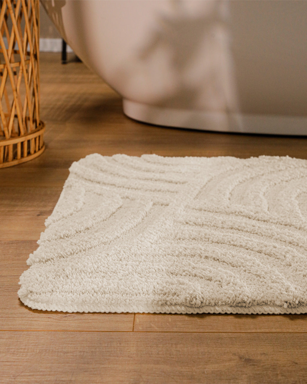 Badteppich von BathKing by WECONhome Fiete Creme Weiß runde Matte im Badezimmer vor Badewanne, Strukturmuster im Flor auf Holzboden sichtbar