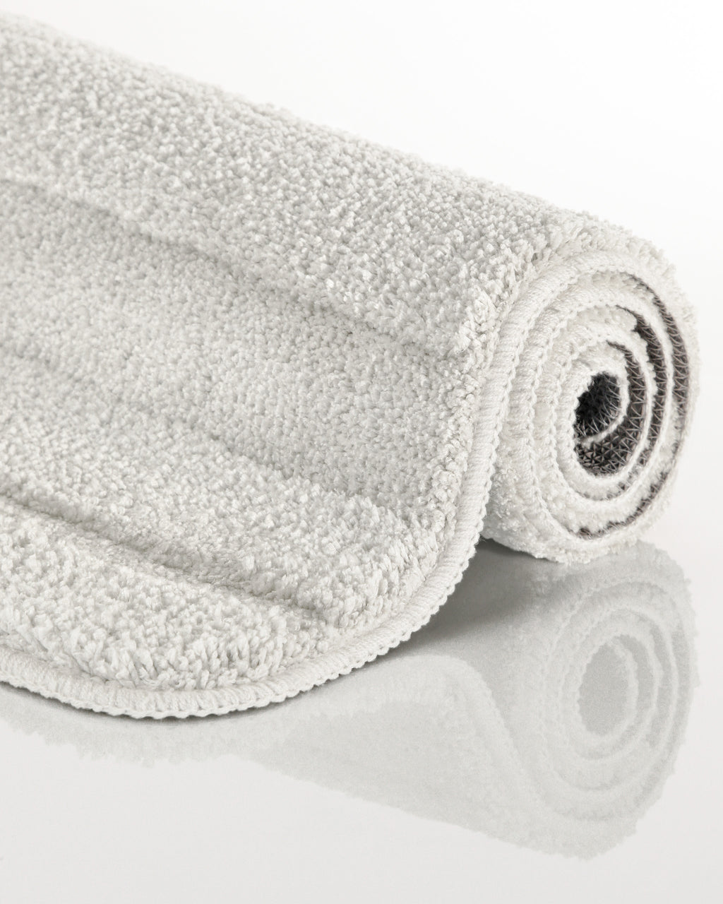 Badteppich von BathKing by WECONhome Marc Weiß aufgerollt auf hellem Hintergrund, Seitenansicht zeigt Florhöhe und Teppichkante