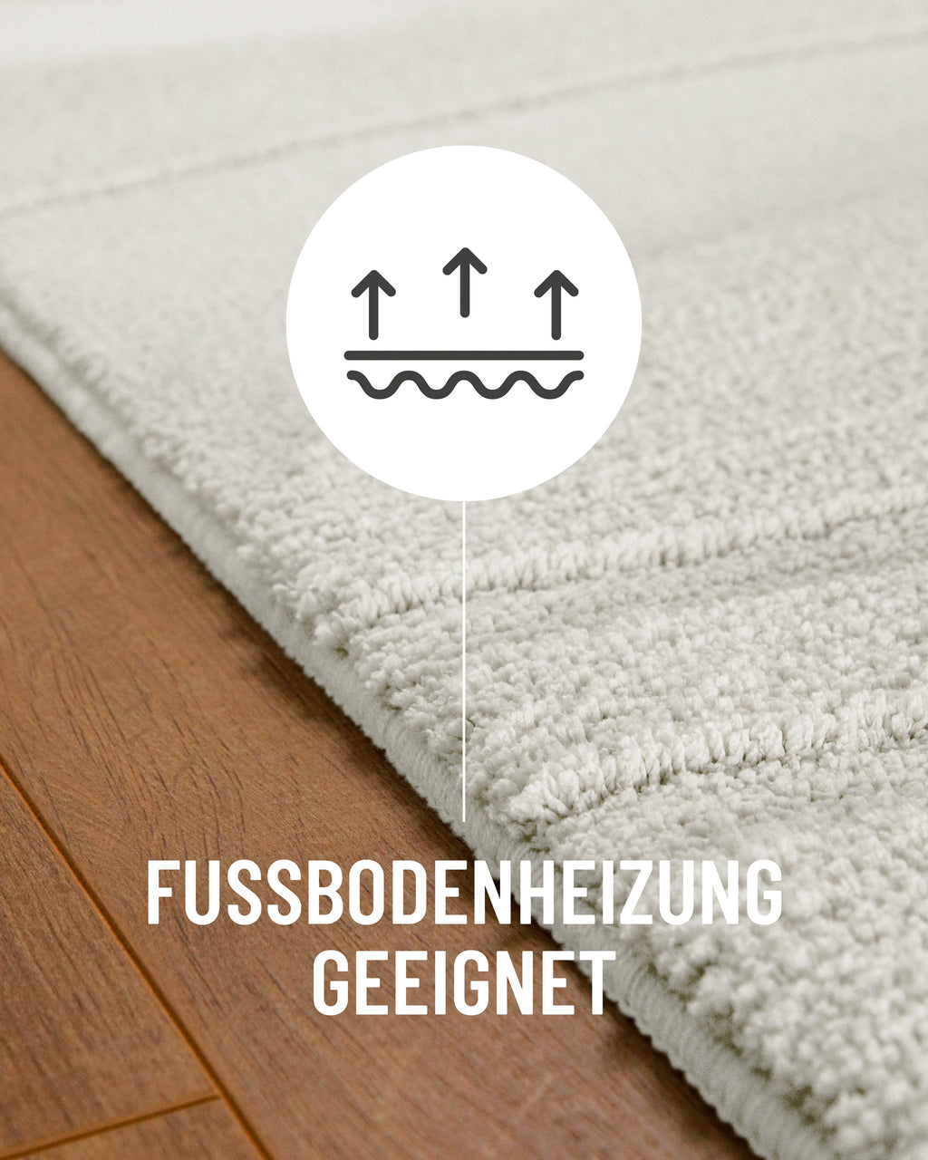 Badteppich von BathKing by WECONhome Marc Weiß Detail auf Holzfußboden mit Symbol für Fußbodenheizung, Nahaufnahme von Flor und Teppichkante