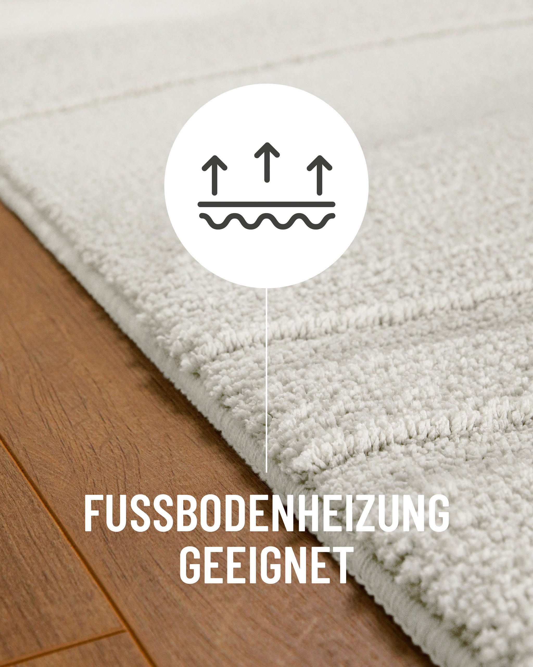 Badteppich von BathKing by WECONhome Marc Weiß Detail auf Holzfußboden mit Symbol für Fußbodenheizung, Nahaufnahme von Flor und Teppichkante