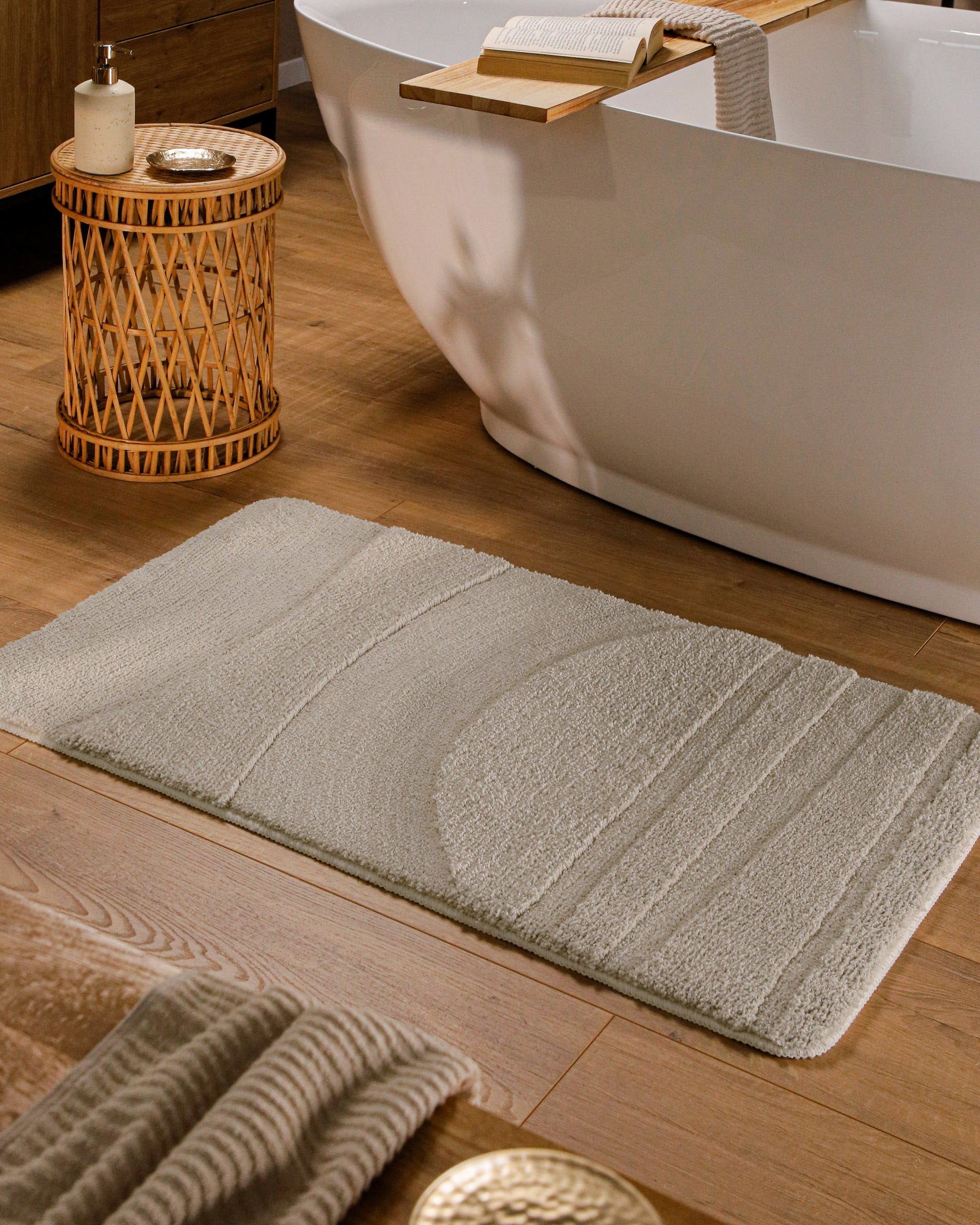 Badteppich von BathKing by WECONhome Marc Grau rechteckig im Badezimmer vor Badewanne auf Holzboden liegend, Strukturmuster im Flor sichtbar