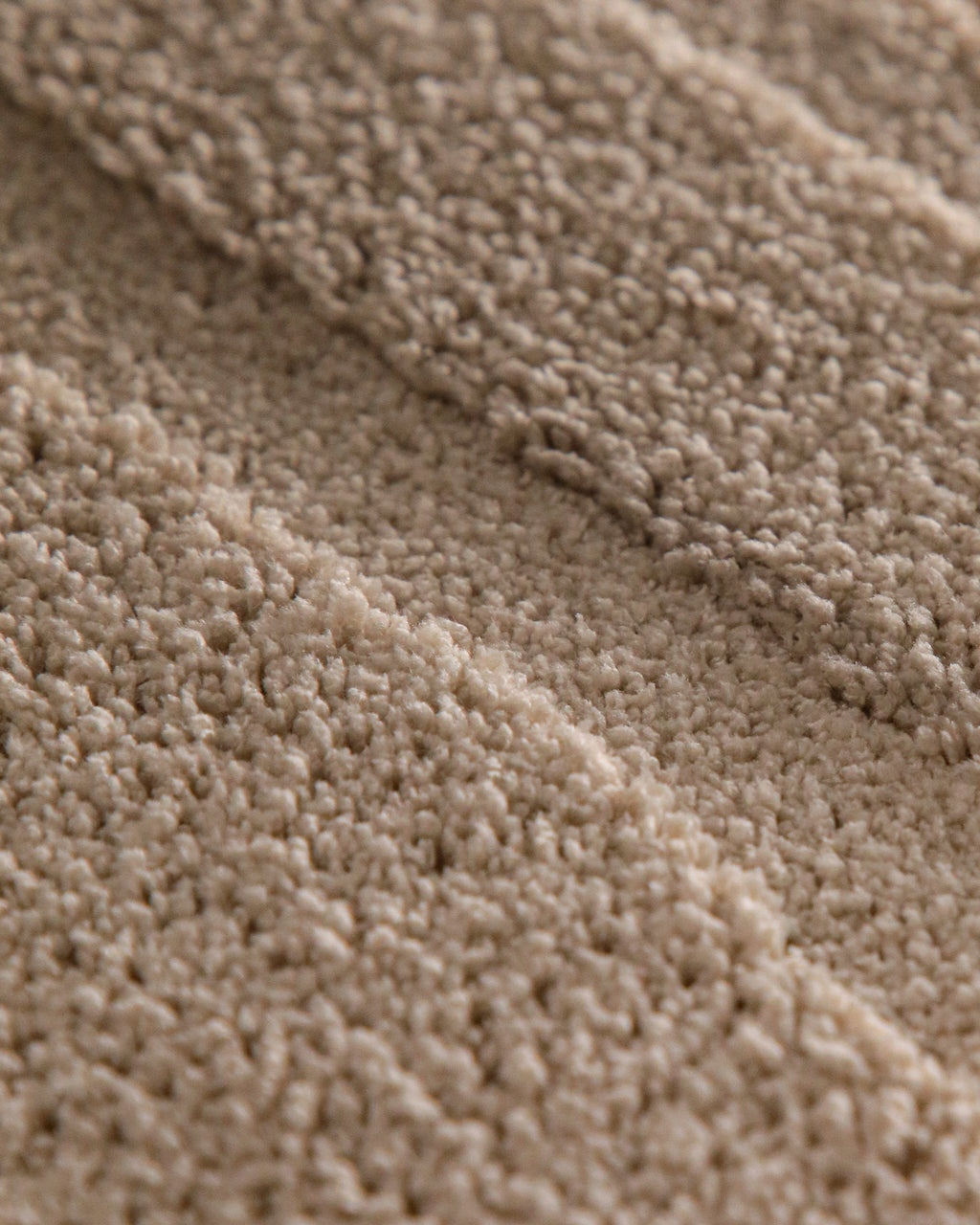 Badteppich von BathKing by WECONhome Marc Sand Beige rund Detail der Teppichkante mit Hinweisen zu maschinengetufteter Verarbeitung