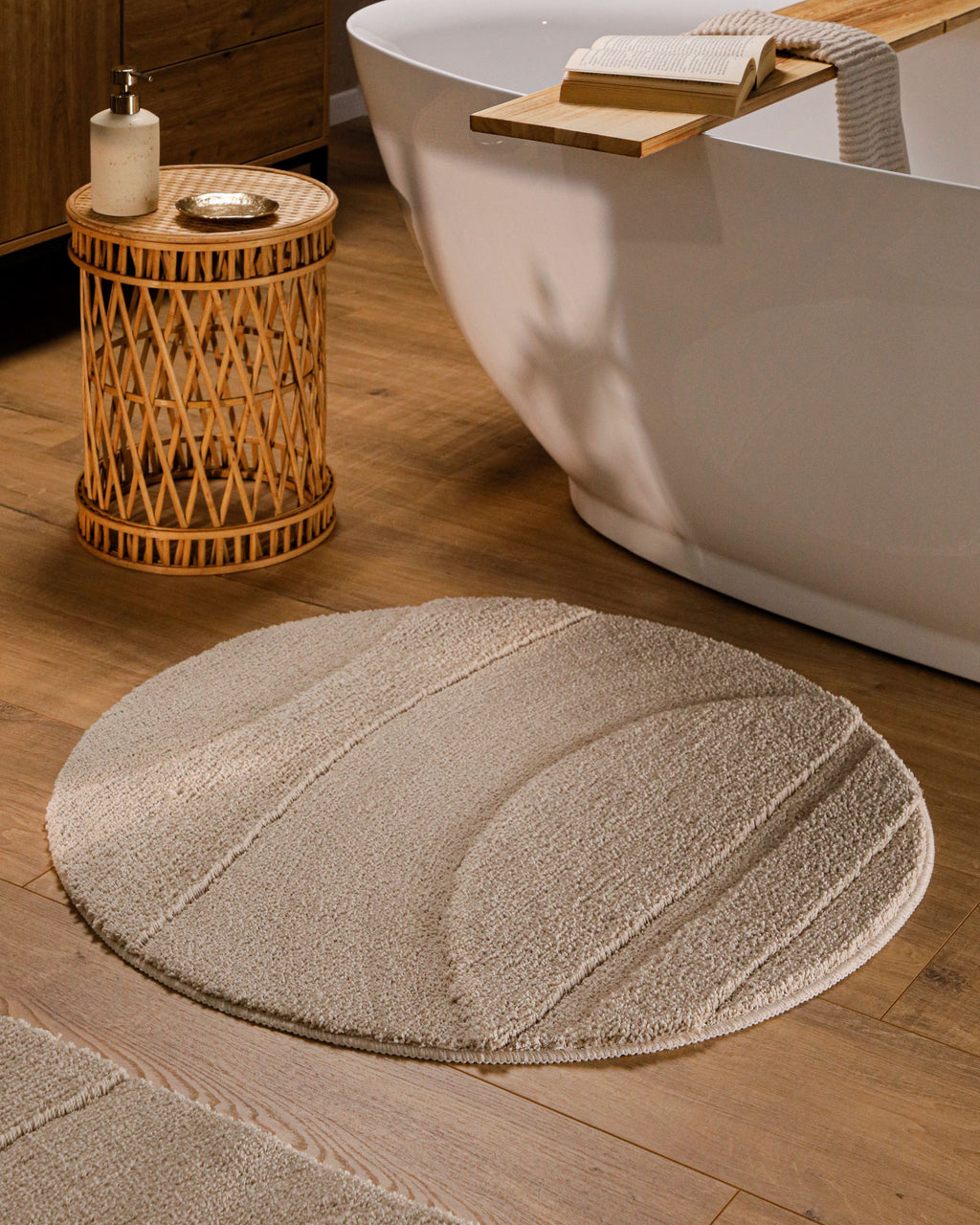 Badteppich von BathKing by WECONhome Marc Sand Beige Detailaufnahme mit umgeschlagener Ecke, Hinweisgrafik zur rutschhemmenden Rückseite und Waschbarkeit