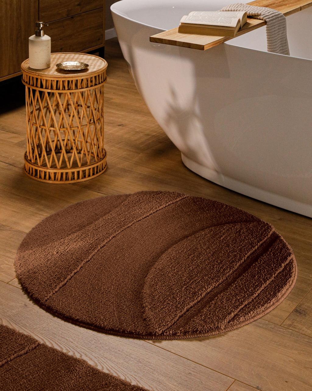 Runder Badteppich von BathKing by WECONhome Marc Braun im Badezimmer vor Badewanne auf Holzboden, strukturiertes Linienrelief im Flor sichtbar