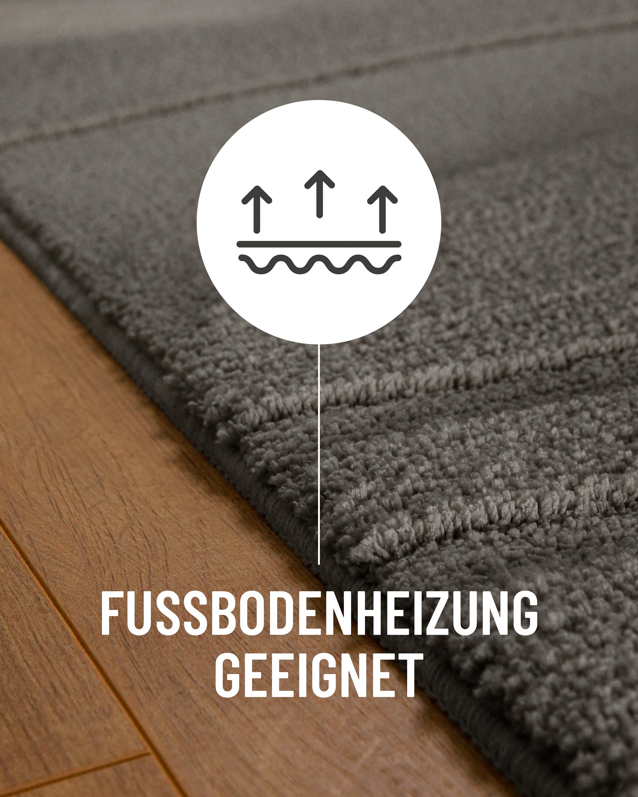 Badteppich von BathKing by WECONhome Marc Basalt Grau Detail auf Holzfußboden mit Symbol für Fußbodenheizung, Nahaufnahme von Flor und Teppichkante