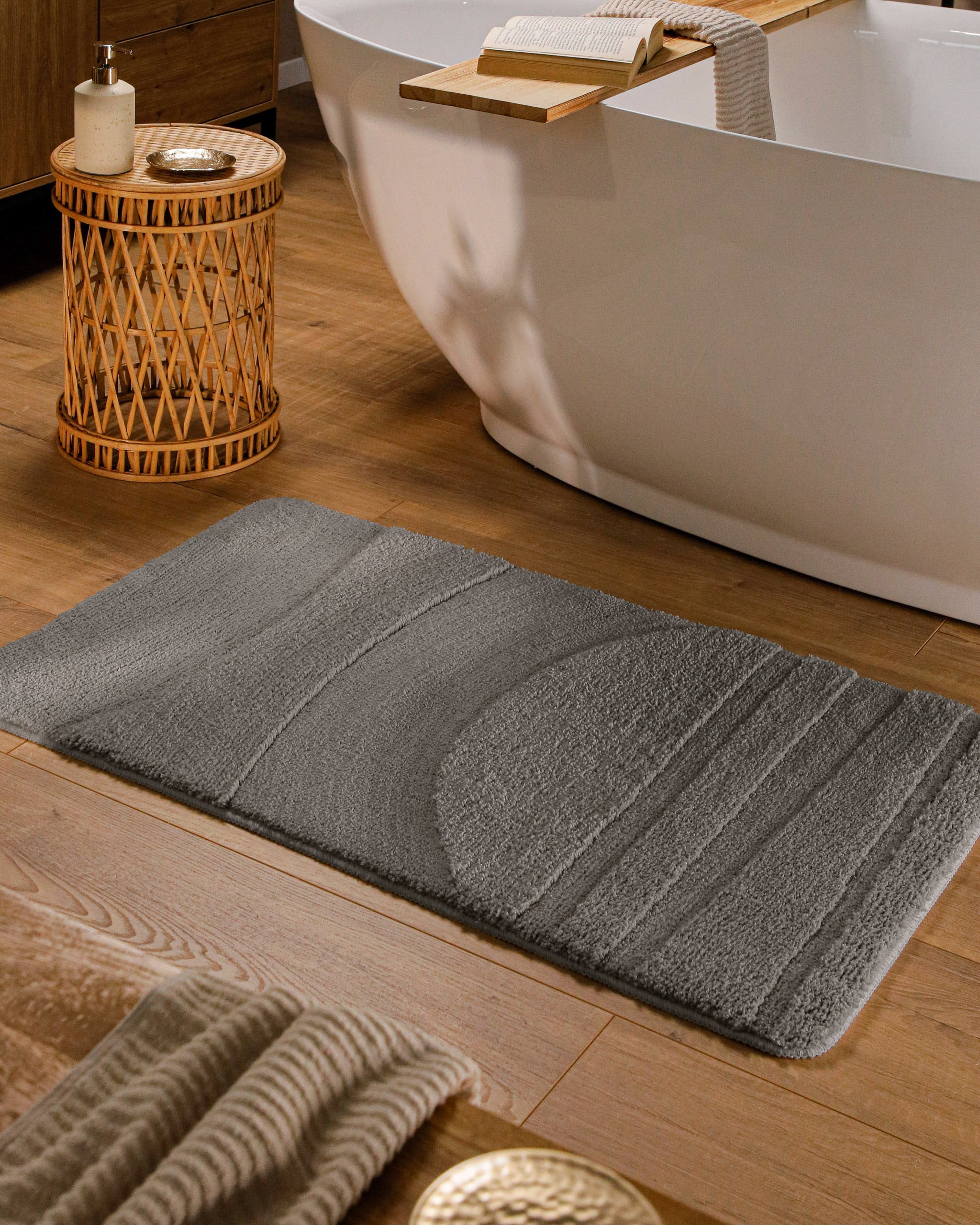 Badteppich von BathKing by WECONhome Marc Basalt Grau rechteckig im Badezimmer vor Badewanne auf Holzboden liegend, Strukturmuster im Flor sichtbar