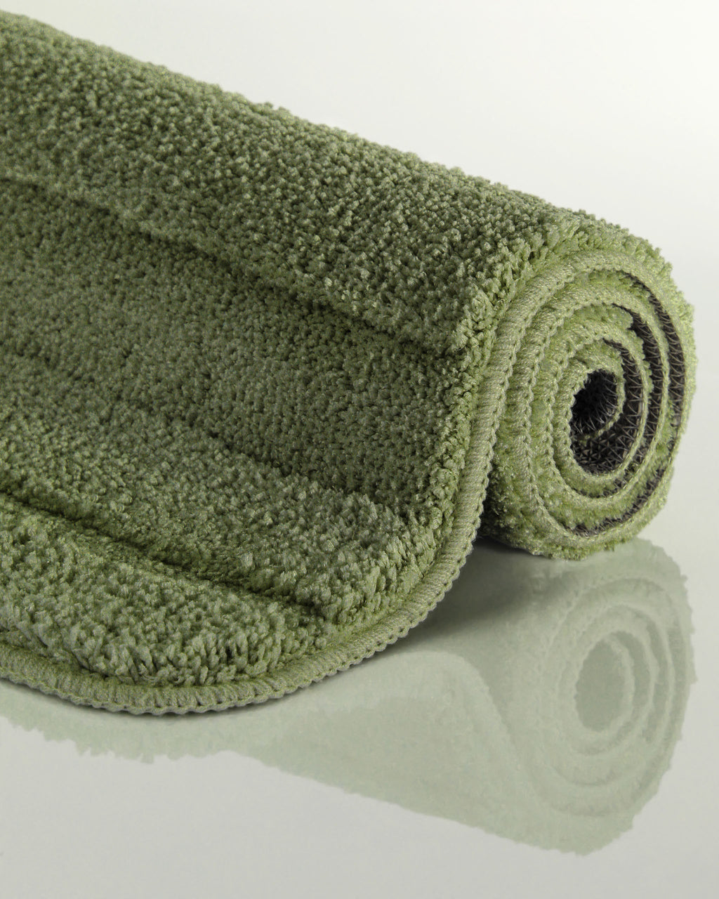 Badteppich von BathKing by WECONhome Marc Reseda Grün aufgerollt auf hellem Hintergrund, Seitenansicht zeigt Florhöhe und Teppichkante