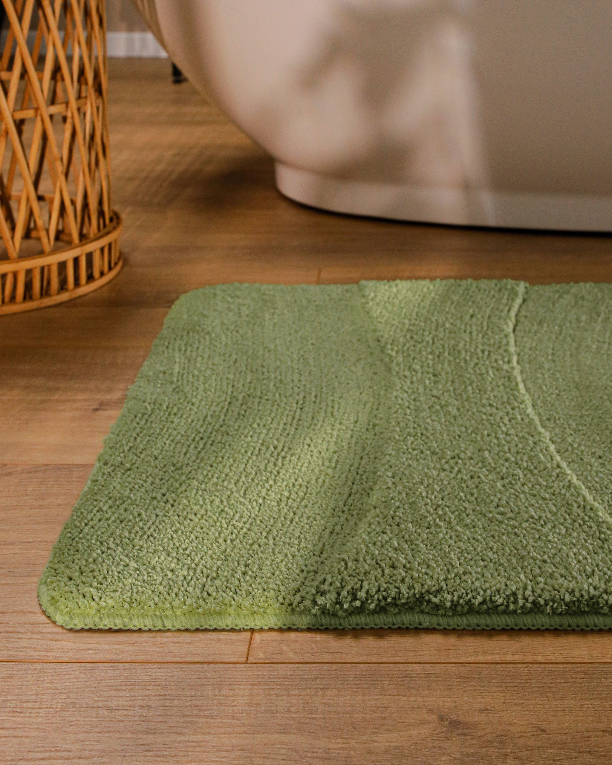 Badteppich von BathKing by WECONhome Marc Reseda Grün runde Matte im Badezimmer vor Badewanne, Strukturmuster im Flor auf Holzboden sichtbar
