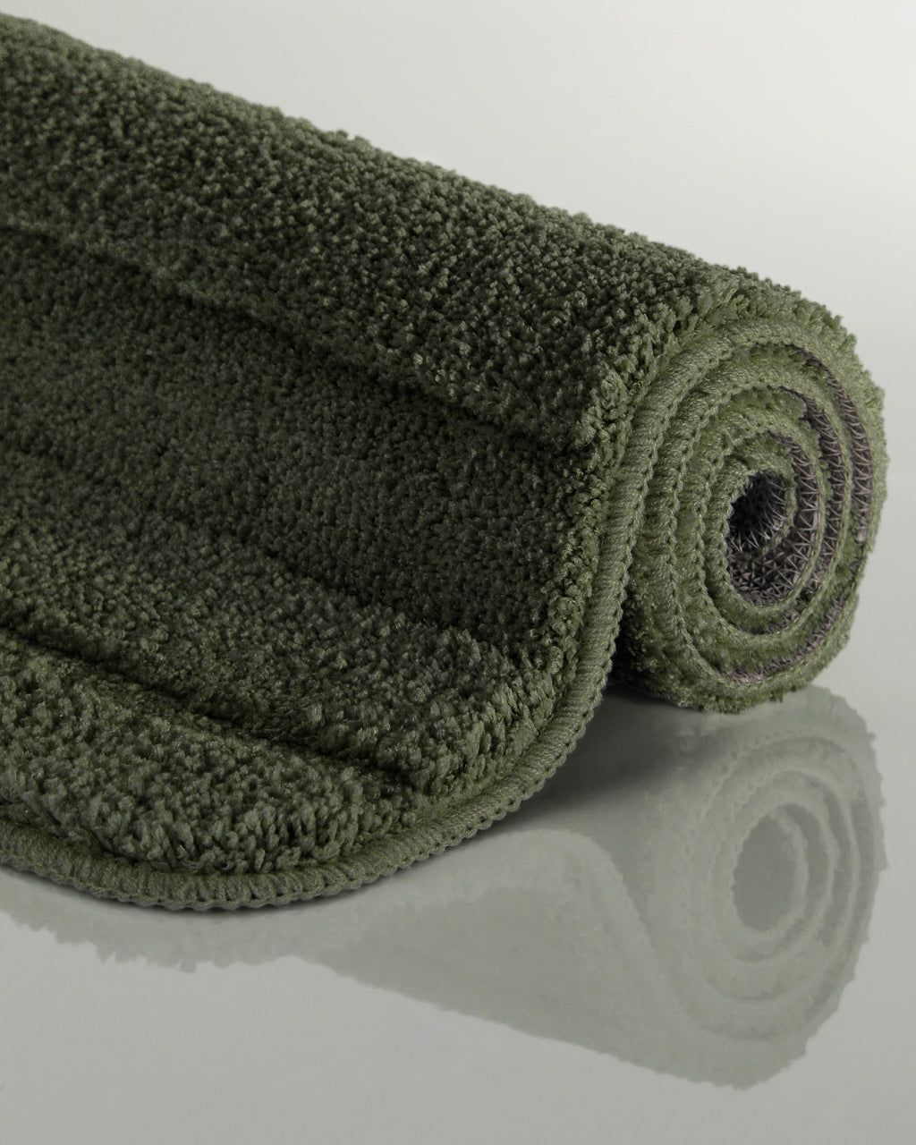 Badteppich von BathKing by WECONhome Marc Kiefer Grün aufgerollt auf hellem Hintergrund, Seitenansicht zeigt Florhöhe und Teppichkante