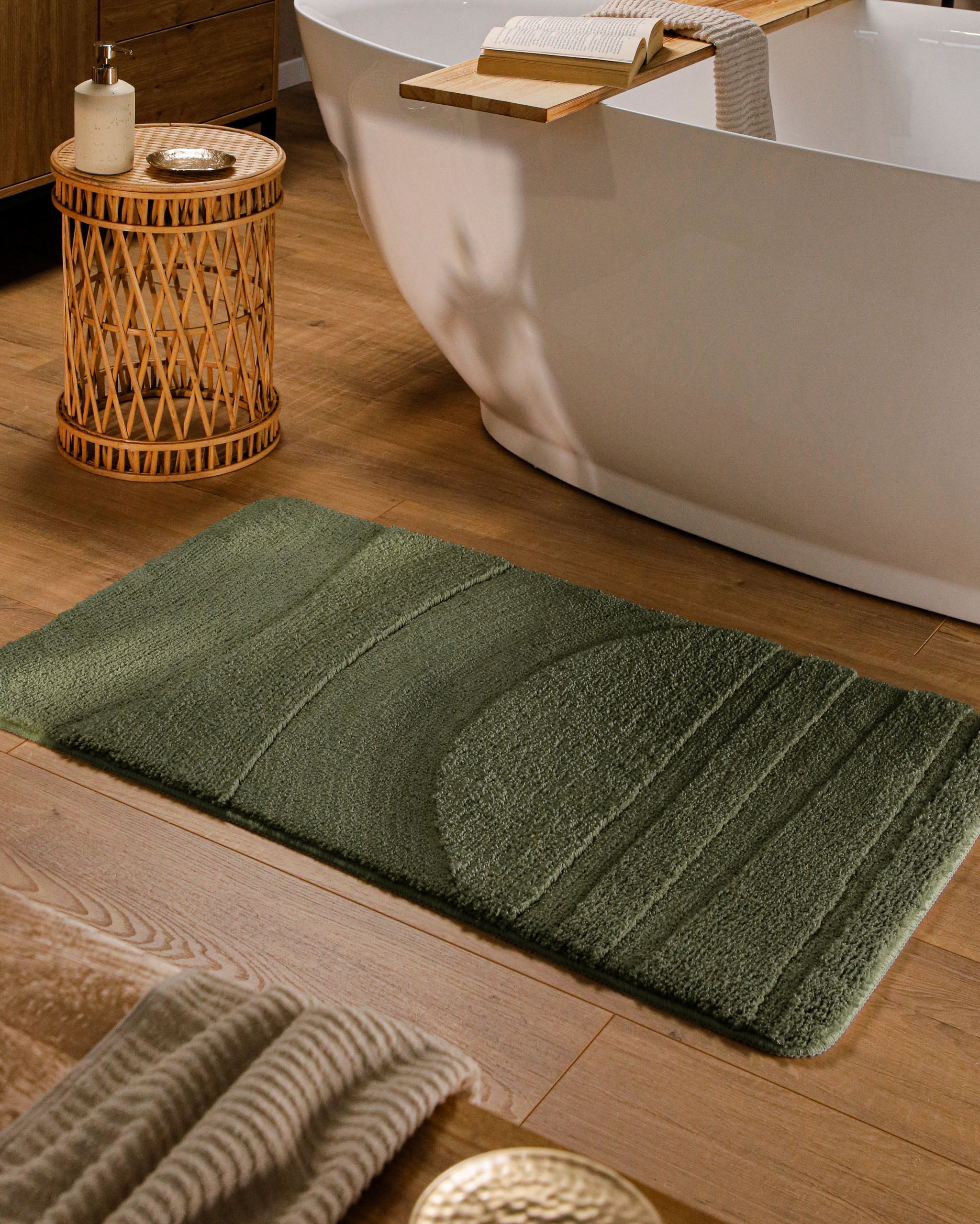 Badteppich von BathKing by WECONhome Marc Kiefer Grün rechteckig im Badezimmer vor Badewanne auf Holzboden liegend, Strukturmuster im Flor sichtbar