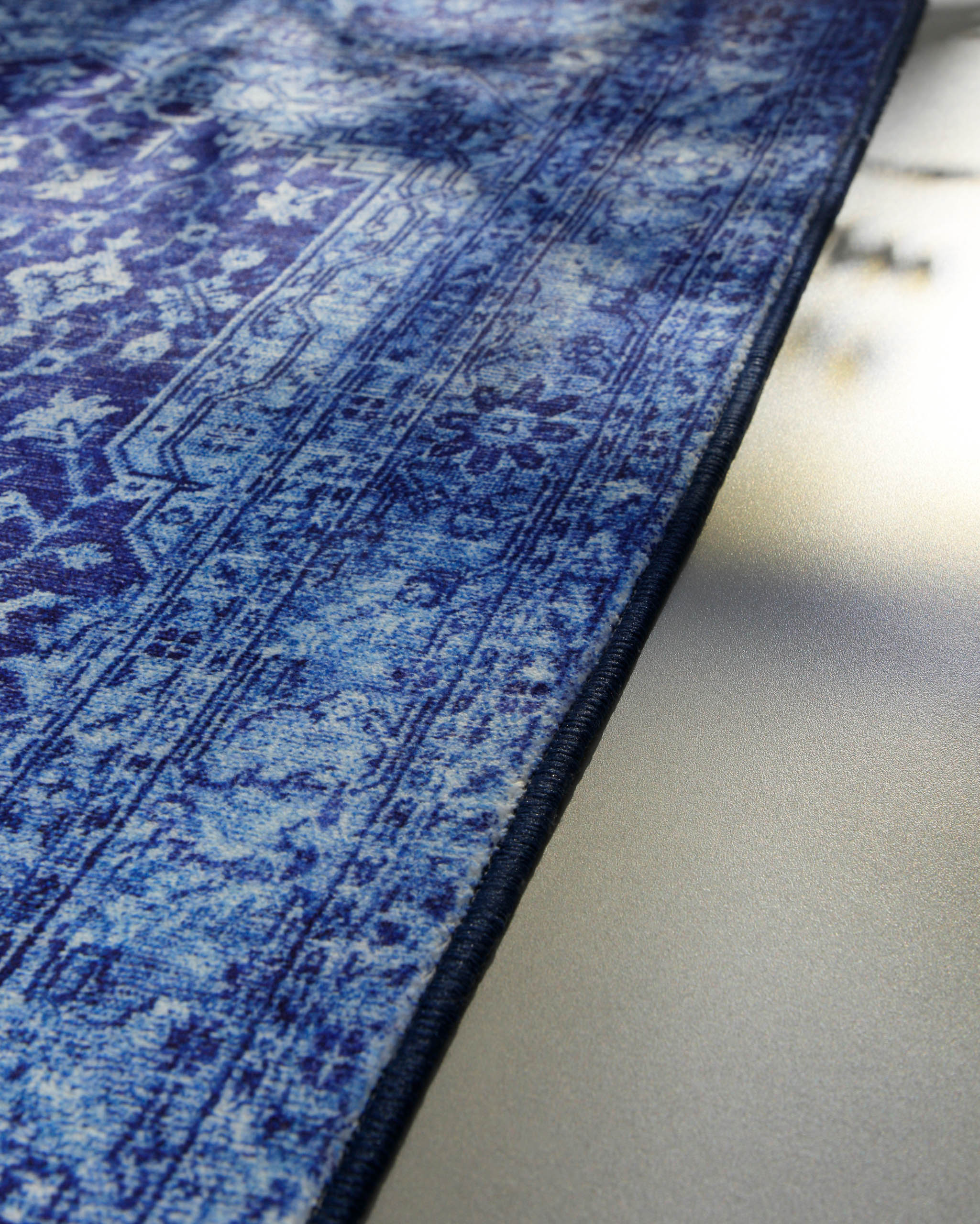 Detailaufnahme der eingefassten Kante des blauen Vintage-Badteppichs Ralph.