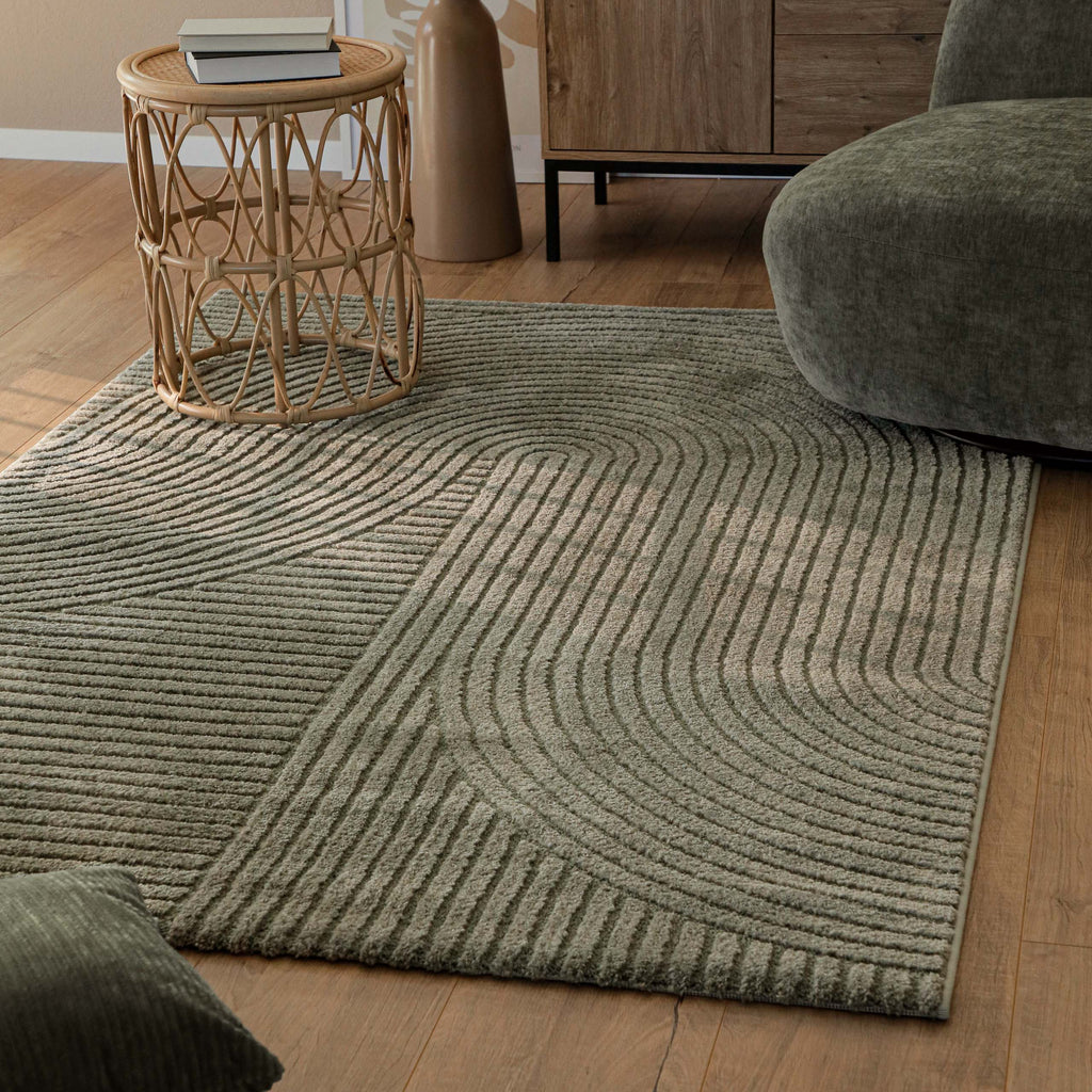 Teppich Bolen oliv grün im Wohnzimmer neben Korbtisch und Sofa, Holzboden