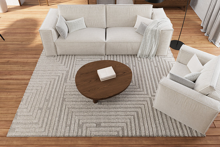 Helles Wohnzimmer mit Couch und Sessel und einem Teppich darunter