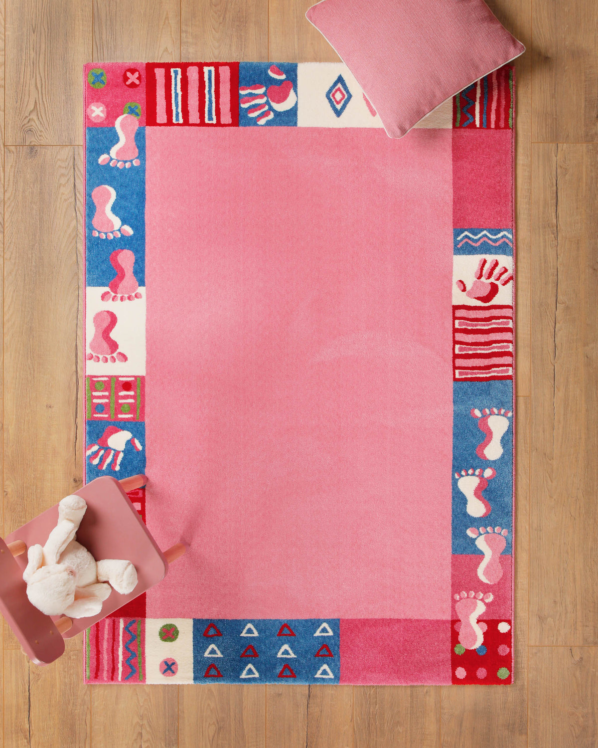 Kinderteppich Hand&Feet in Rosa auf Holzboden mit Teddybär in der Ecke