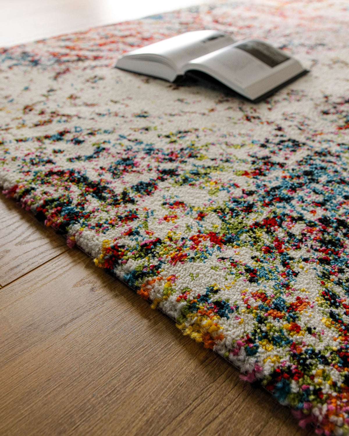 Kurzflorteppich Multi "Modernina 2.0" von WECONhome, Lifestyle-Aufnahme mit Buch auf dem Teppich