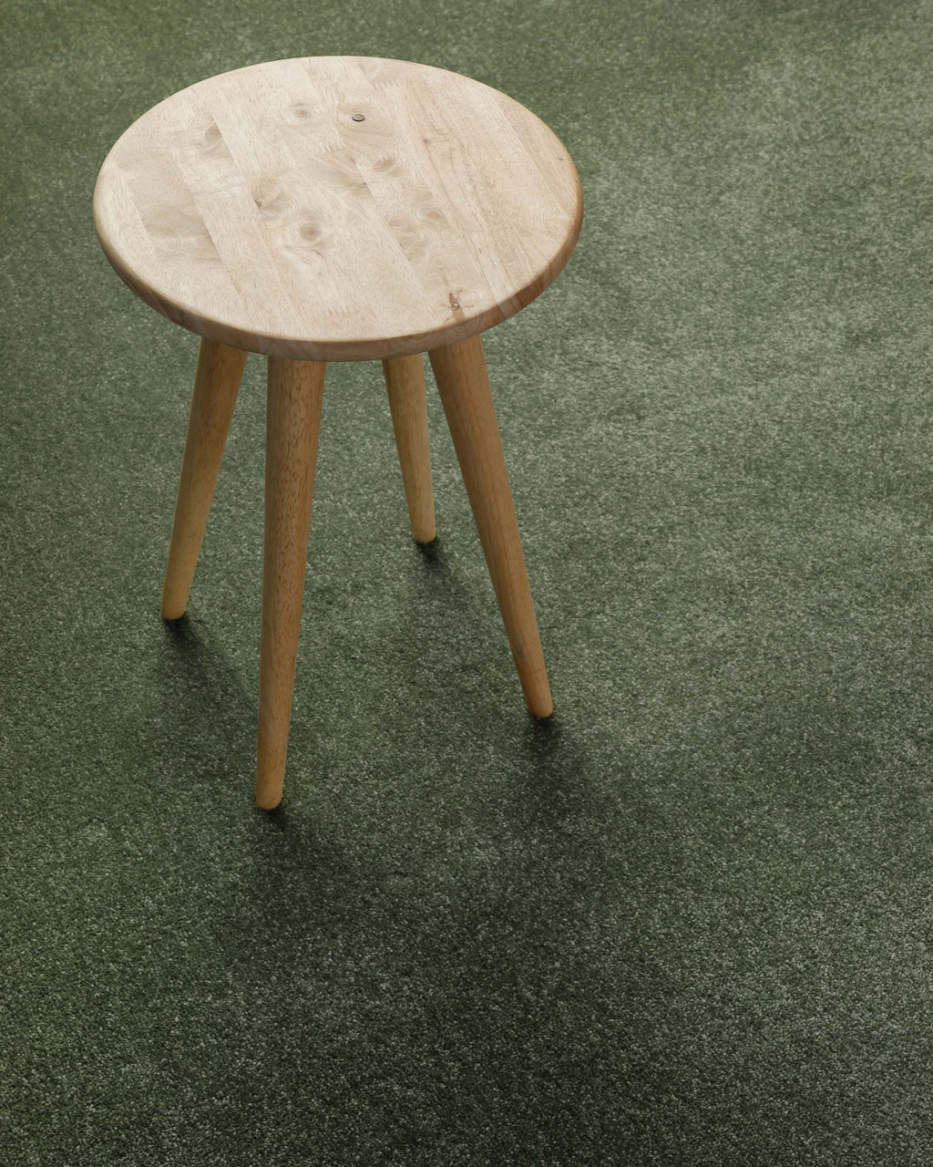 Kurzflor Teppich Montepulciano Laub Grün im Wohnraum mit Hocker