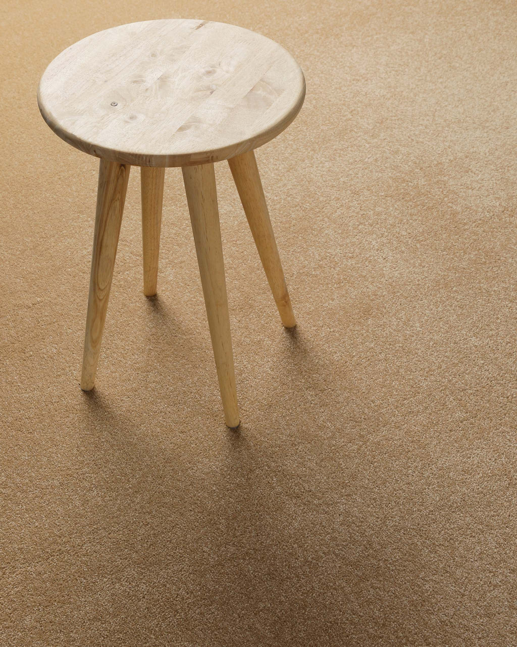 Kurzflor Teppich Montepulciano Sand Beige im Wohnraum mit Hocker auf warmer Oberfläche