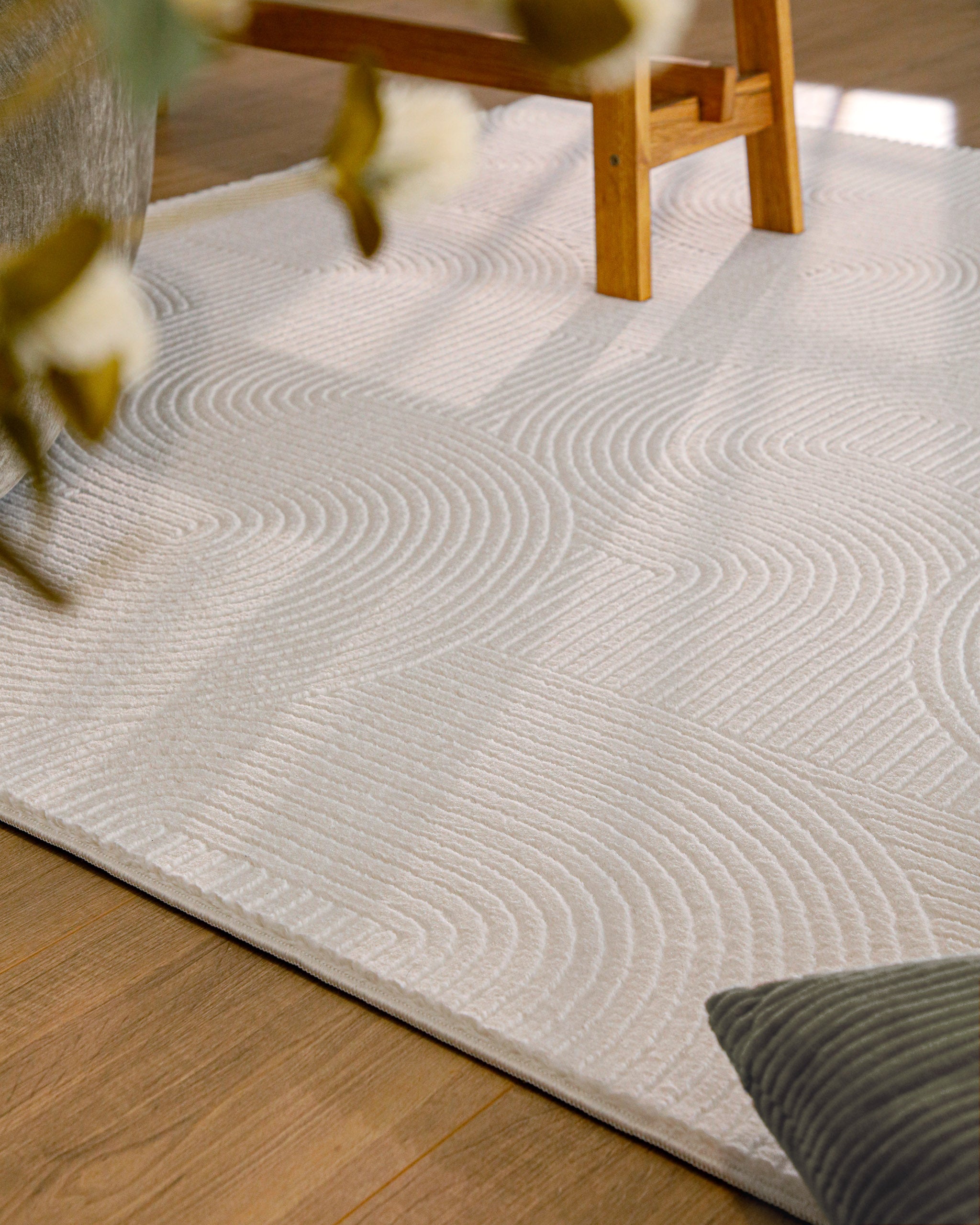 Detailansicht WECONhome Kurzflorteppich Nuuk Arc in Creme Weiß unter einem Holztisch