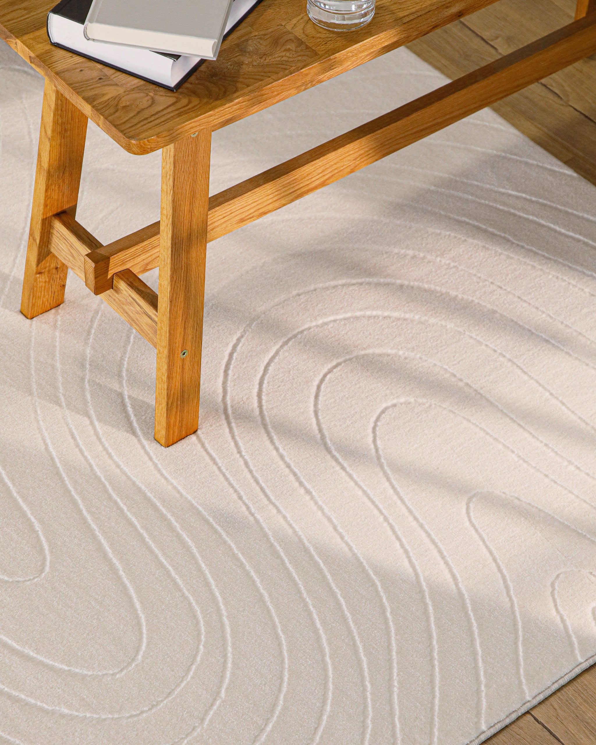 Nuuk Flow Teppich creme modernes Relief Wellenoptik unter einem Holztisch