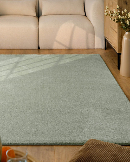 Kurzflor Teppich Vegas Hellgrün im Wohnzimmer vor Sofa auf Holzboden, gleichmäßige Oberfläche mit hellem Farbton