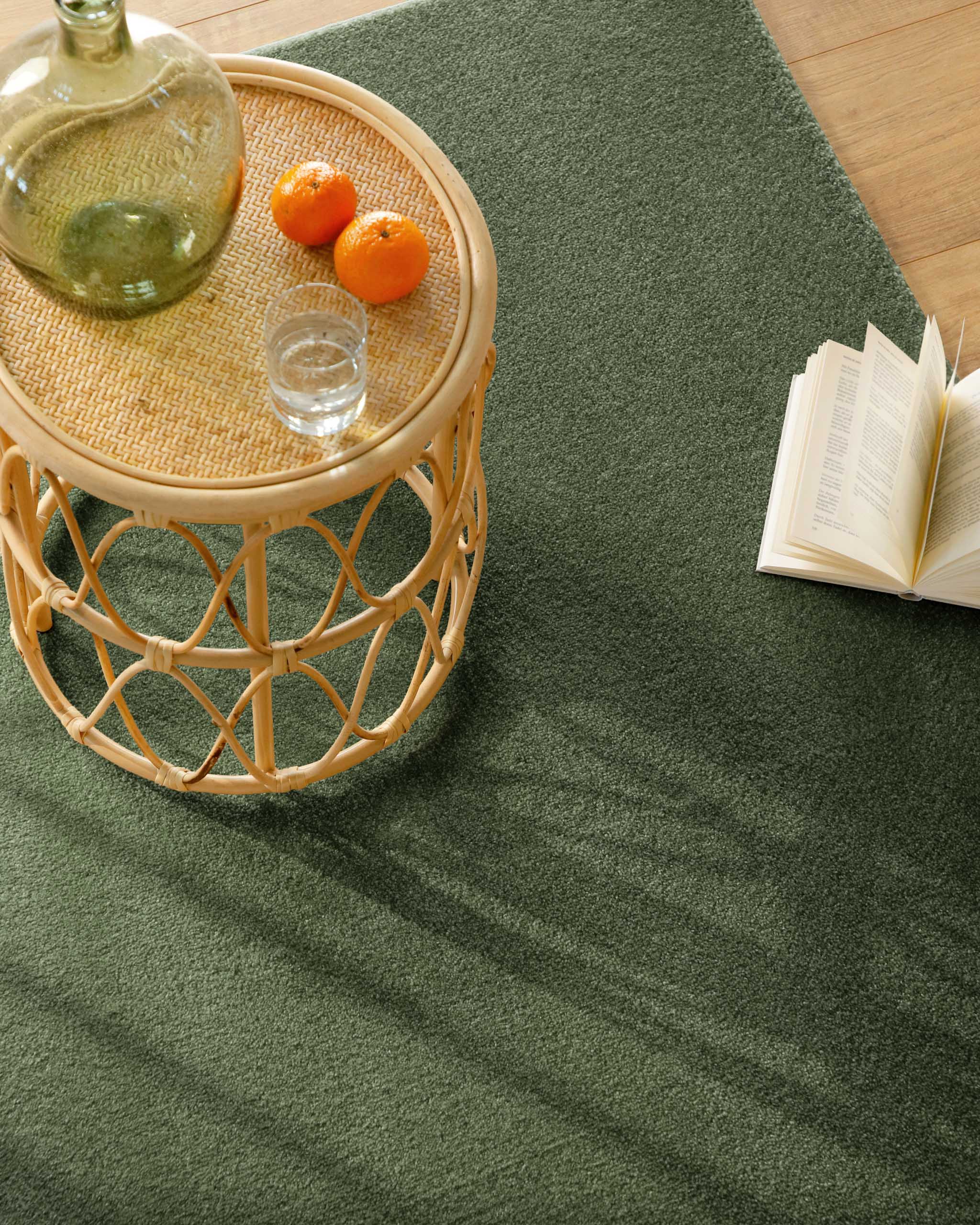 Kurzflor Teppich Vegas Grün Nahaufnahme im Wohnraum, Beistelltisch mit Glas und Buch auf der Teppichfläche